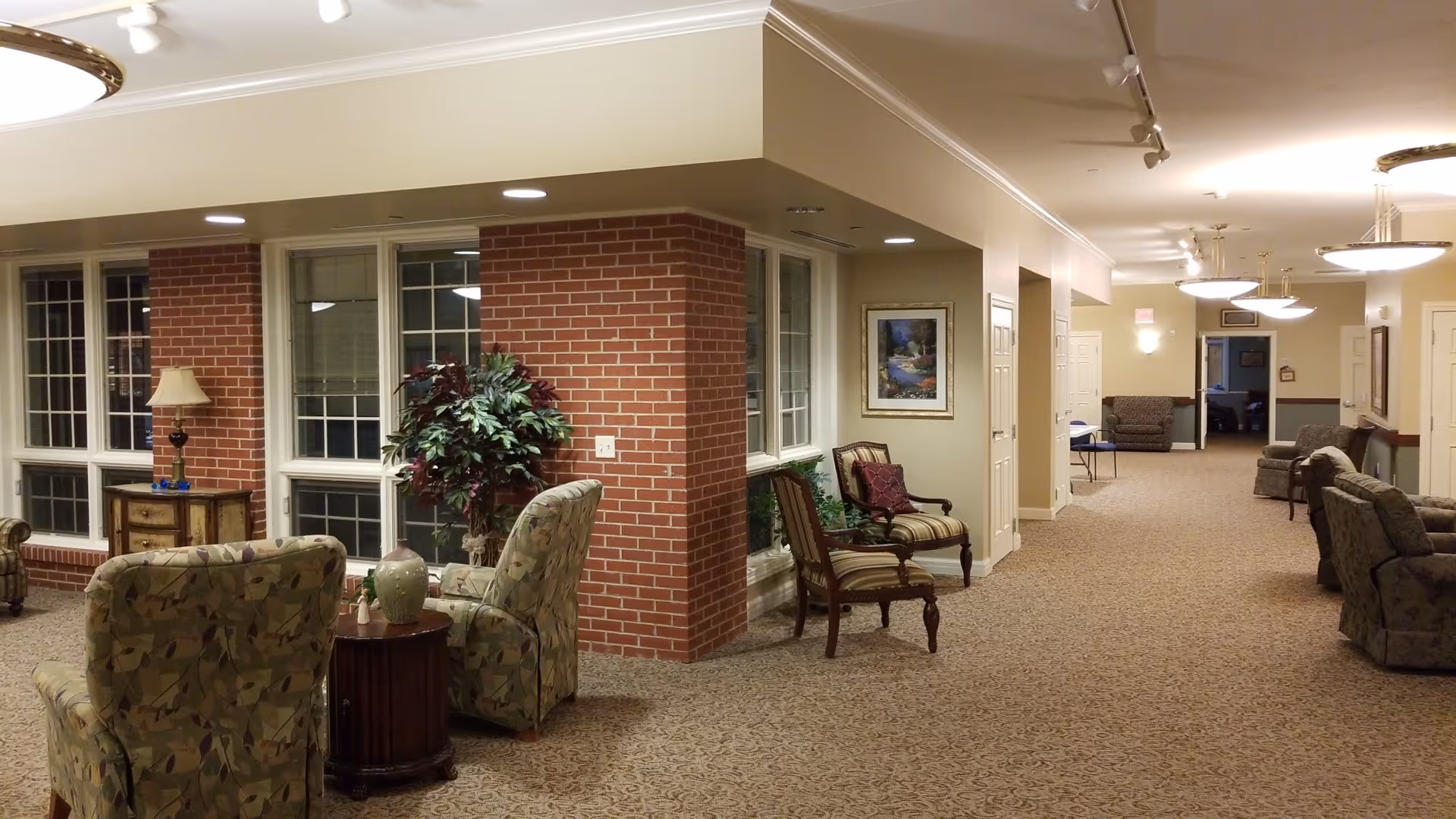 Interior lounge area with brick columns, large windows, and upholstered seating.