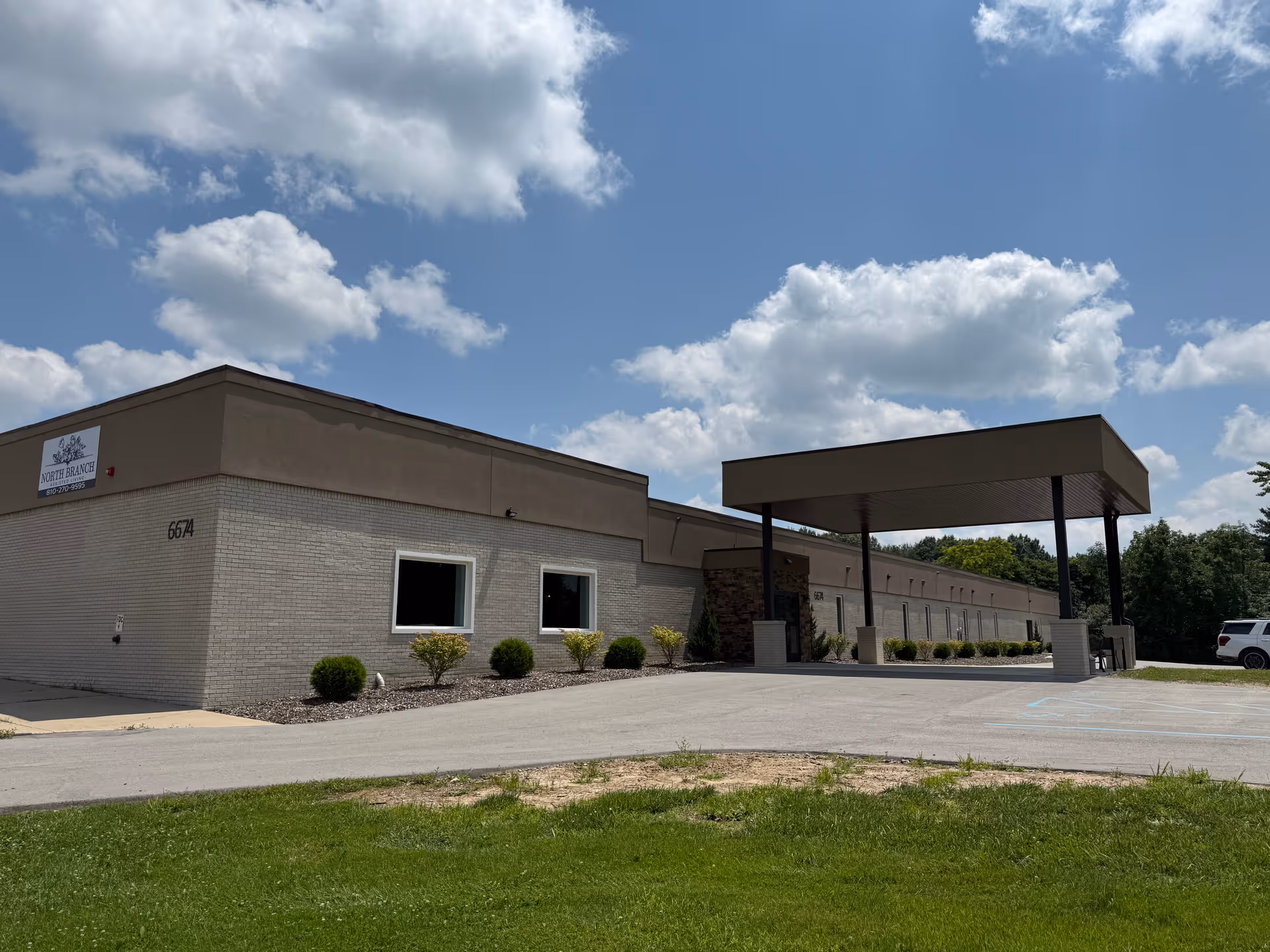 Exterior view of North Branch Assisted Living building with a covered entrance and landscaping.