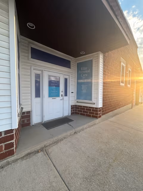 Exterior view of Elite Personal Care LLC entrance with glass door and sign.