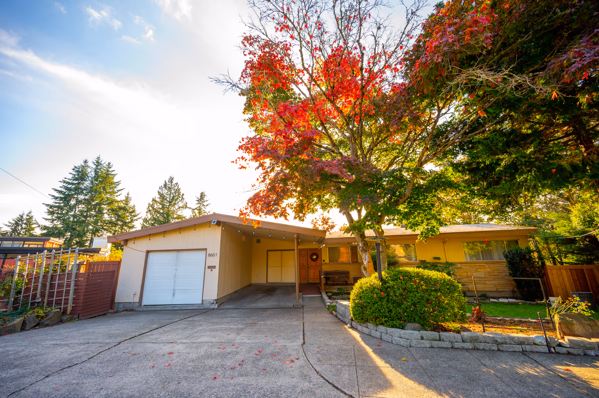 Single-story residential front of Spada Homes, Inc., with driveway, garage, and autumn trees.