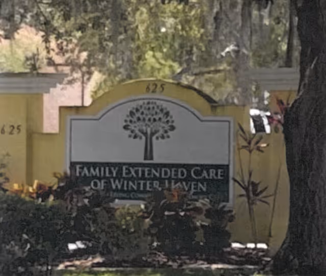 Exterior view of the facility entrance sign reading Family Extended Care of Winter Haven with greenery.