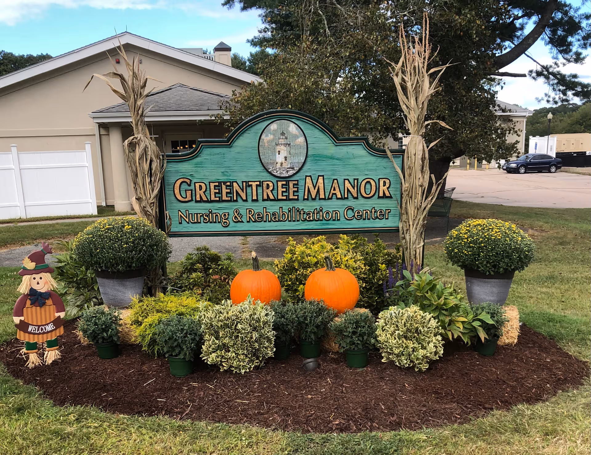 Exterior view of Greentree Manor Nursing and Rehabilitation Center sign with pumpkins and landscaping.