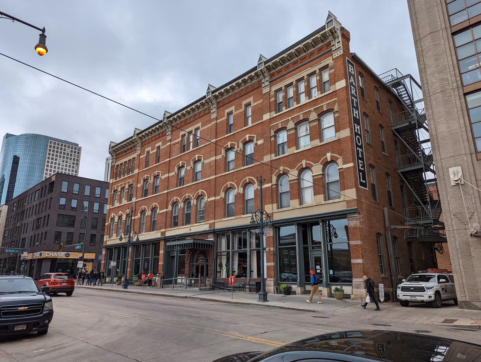 Brick Barth Hotel building on a city street with pedestrians and storefronts.