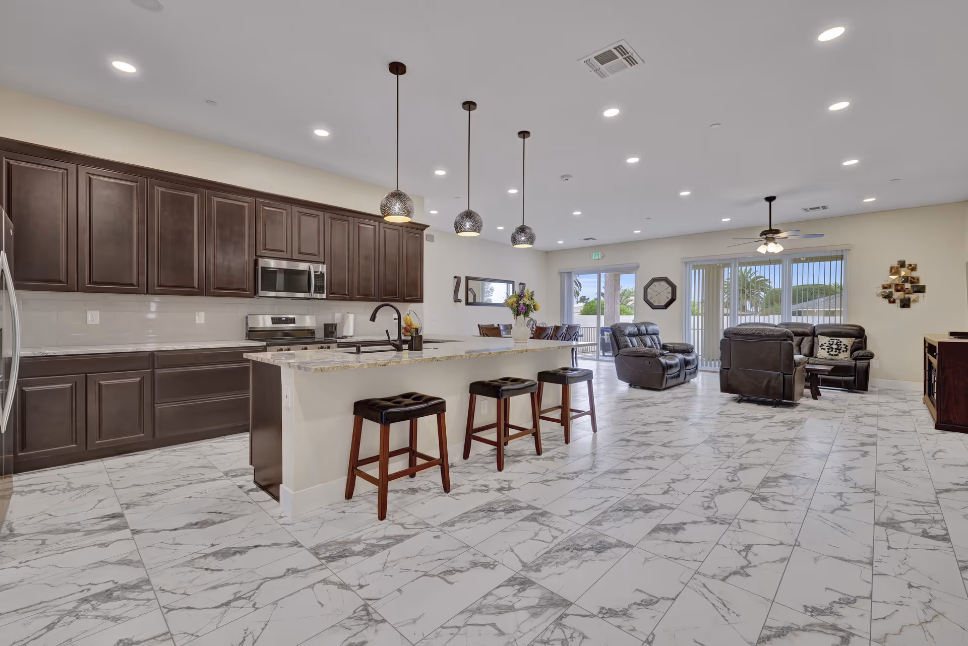 Open-concept senior living area with dark kitchen cabinets, island, bar stools, and seating.