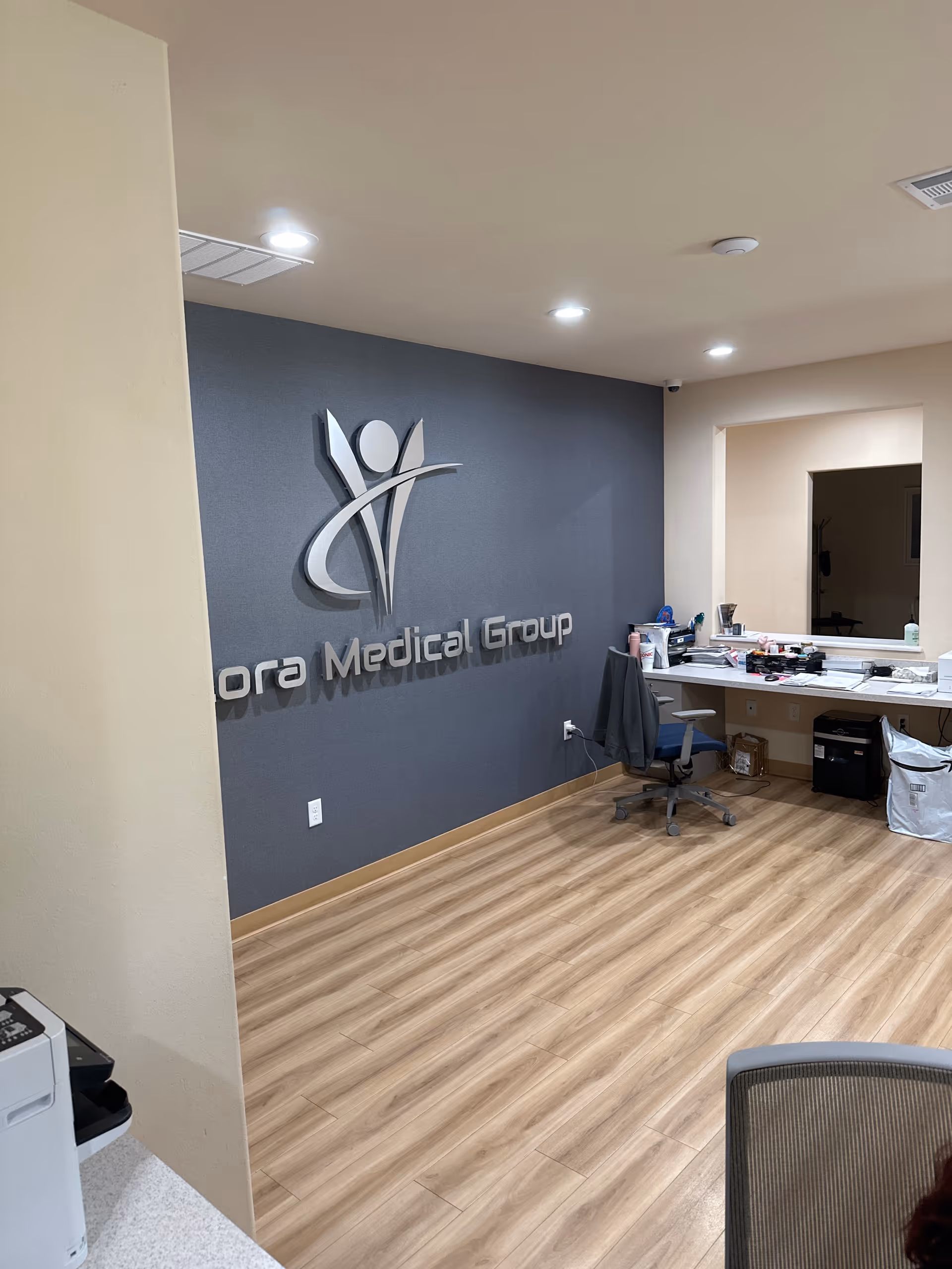 Reception area with a logo wall and desk in a medical facility.
