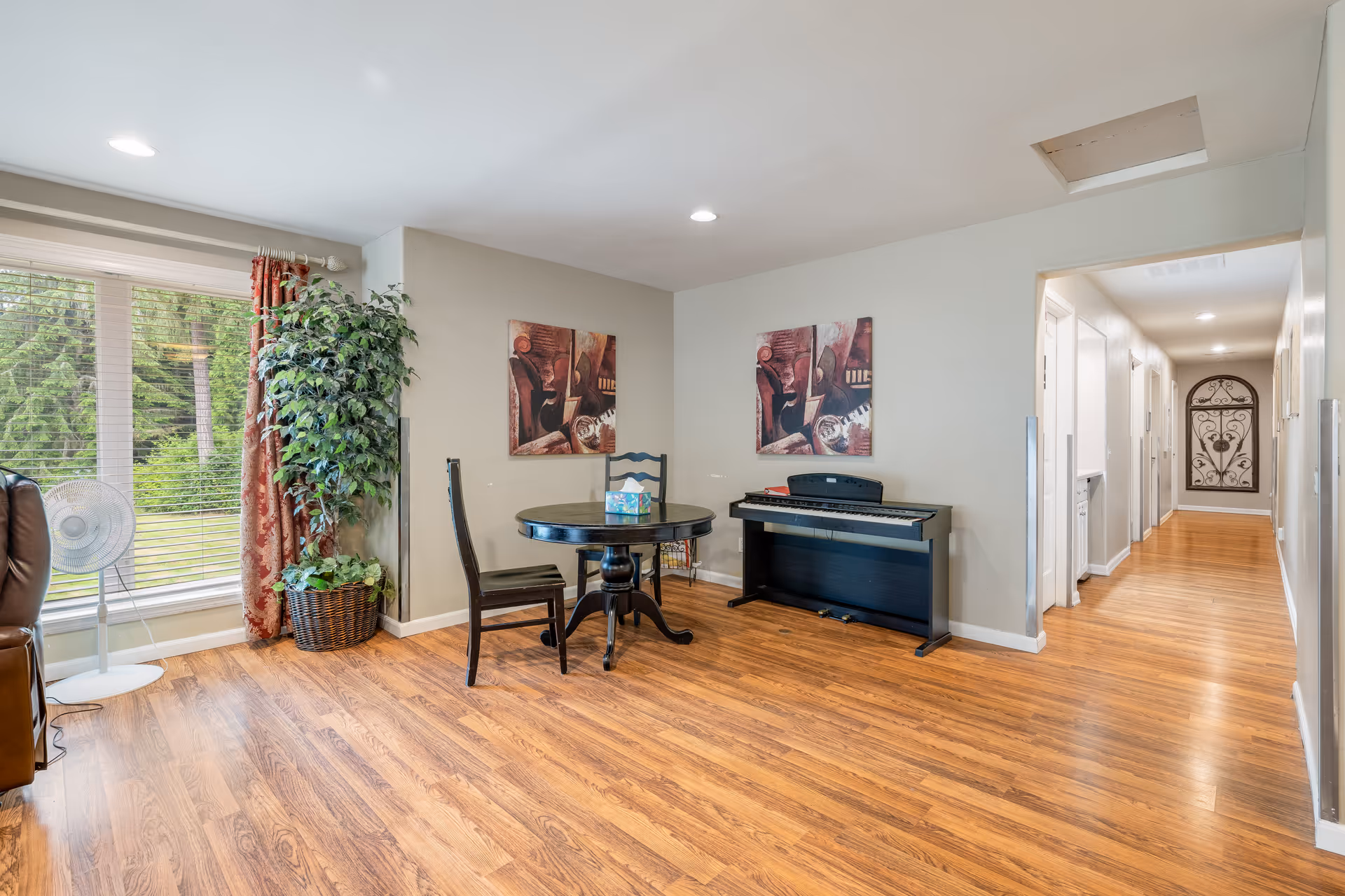Bright living area with piano, round table, art, and large window.