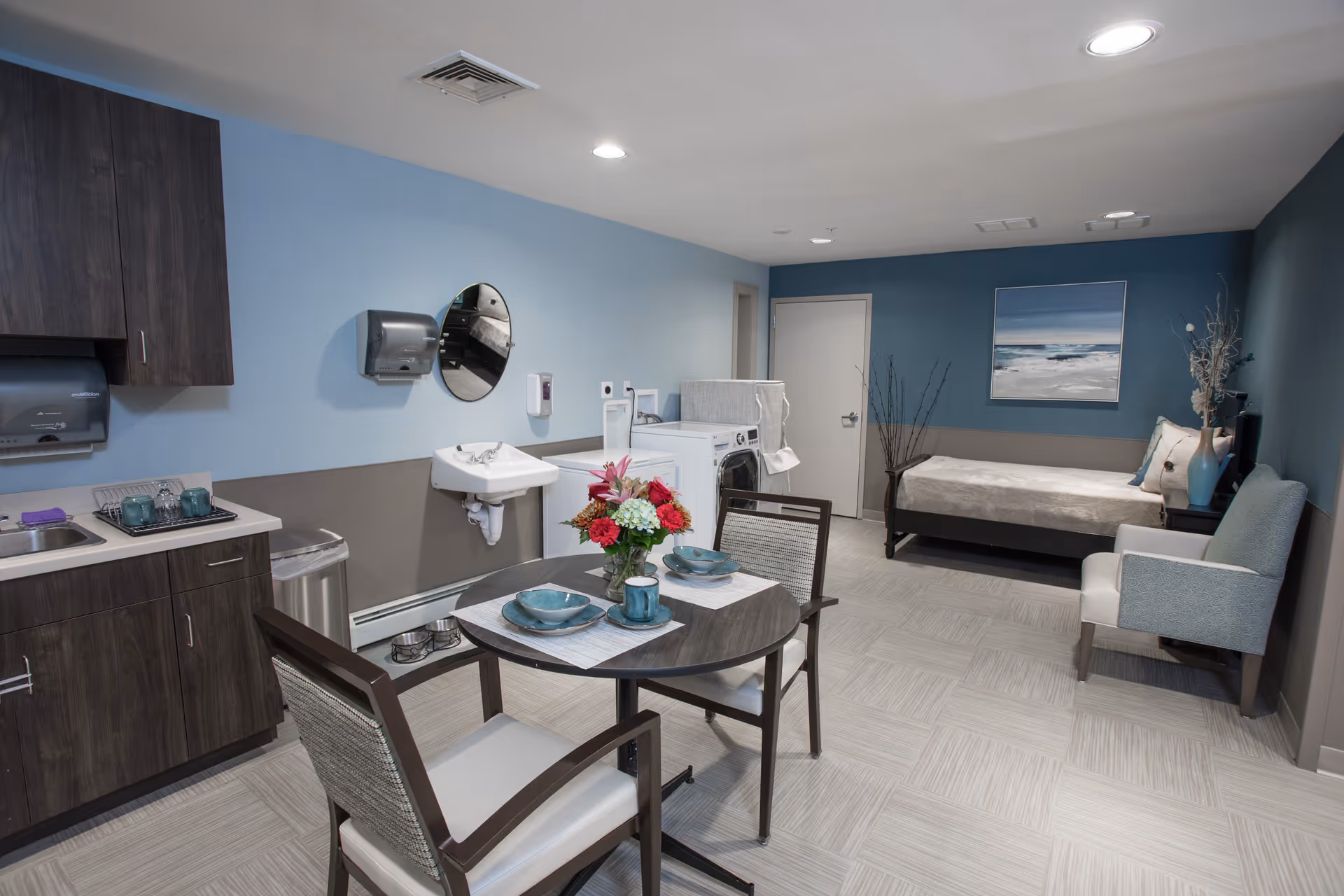Studio apartment with kitchenette, dining table, seating area, and a bed.