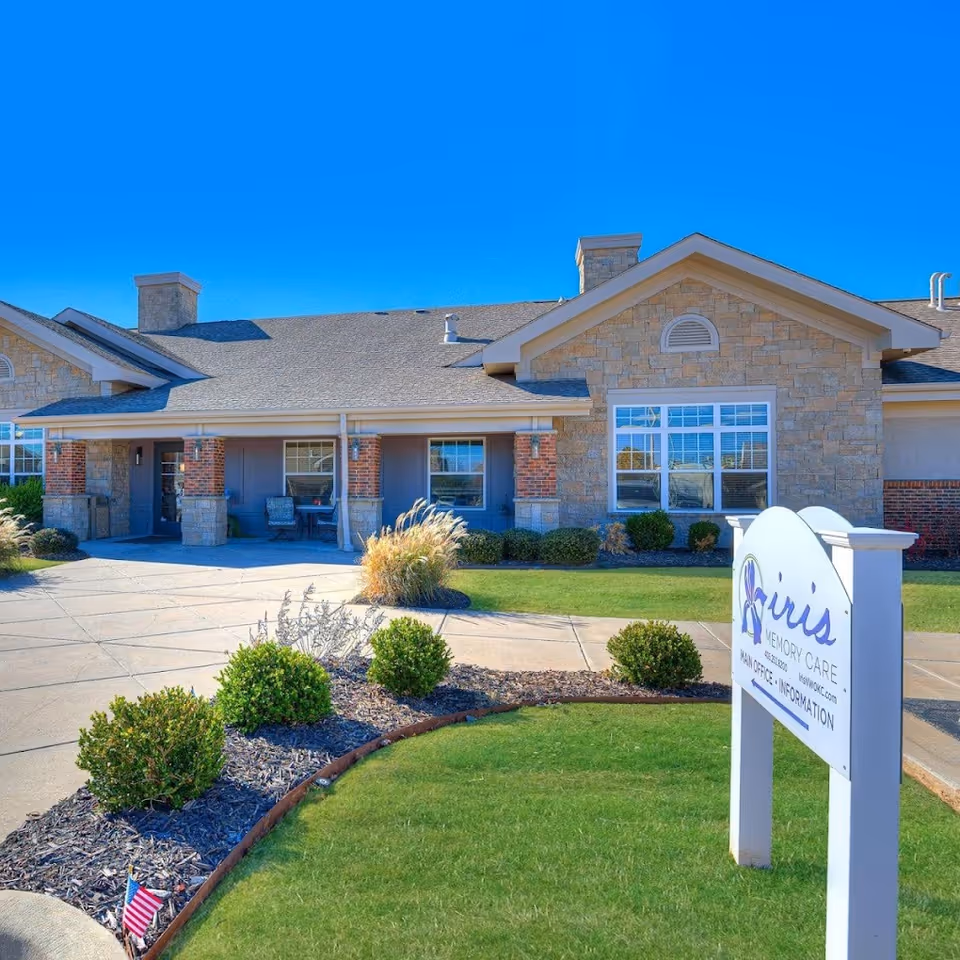 Front exterior of Iris Memory Care Tulsa building with sign and landscaping.