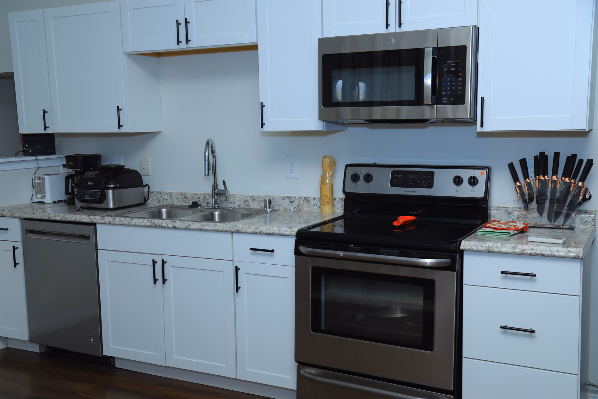 Modern kitchen with white cabinets, stainless steel appliances, granite countertops, and a double sink.