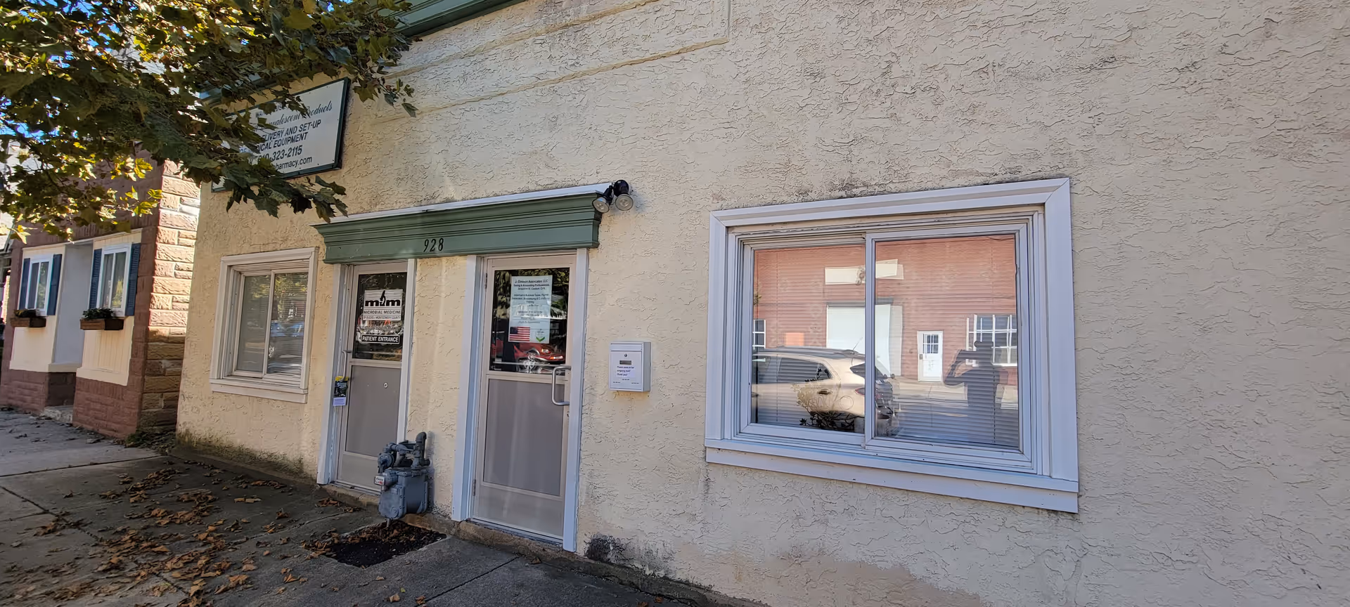 Exterior of a beige building with a green awning, glass door, and window.