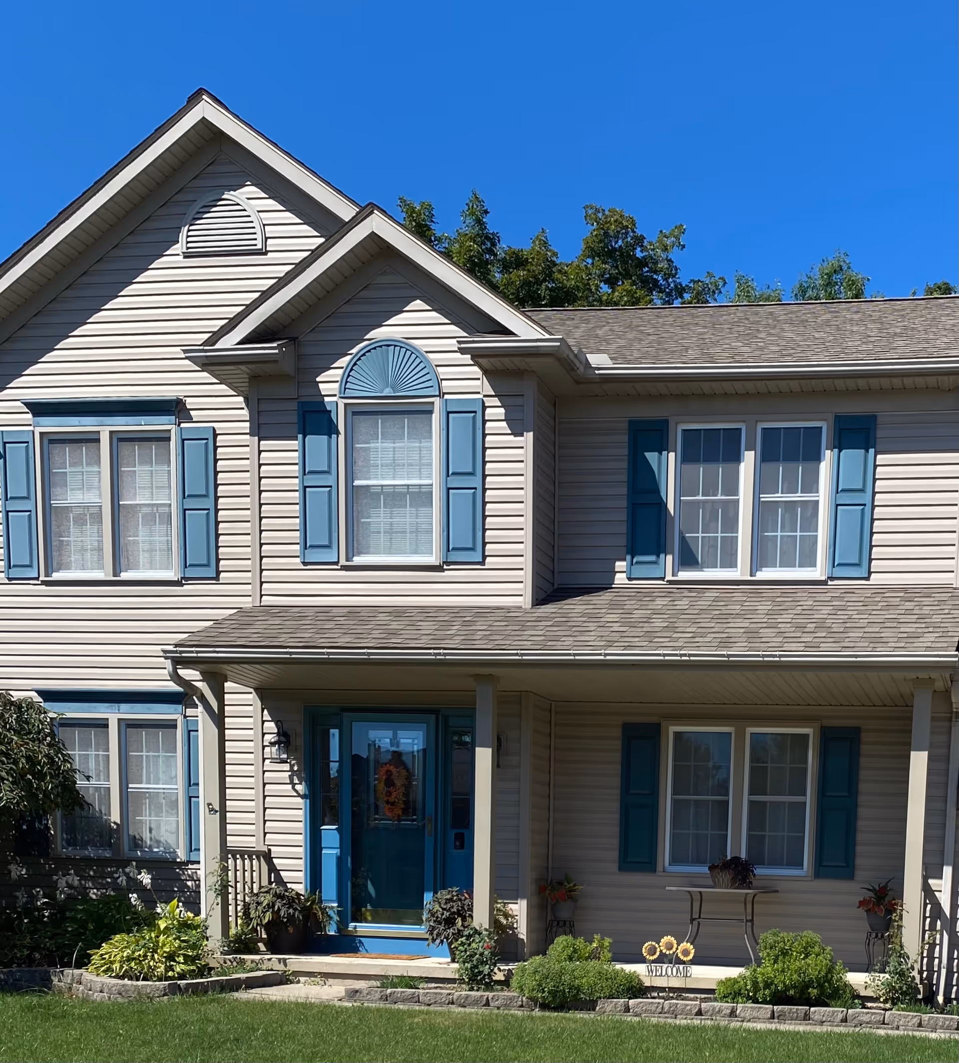 Two-story beige building with blue shutters and a welcoming front porch.