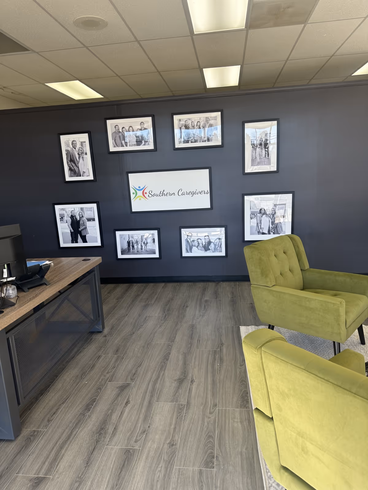 Office lobby featuring a dark wall with framed photos and lime-green chairs.