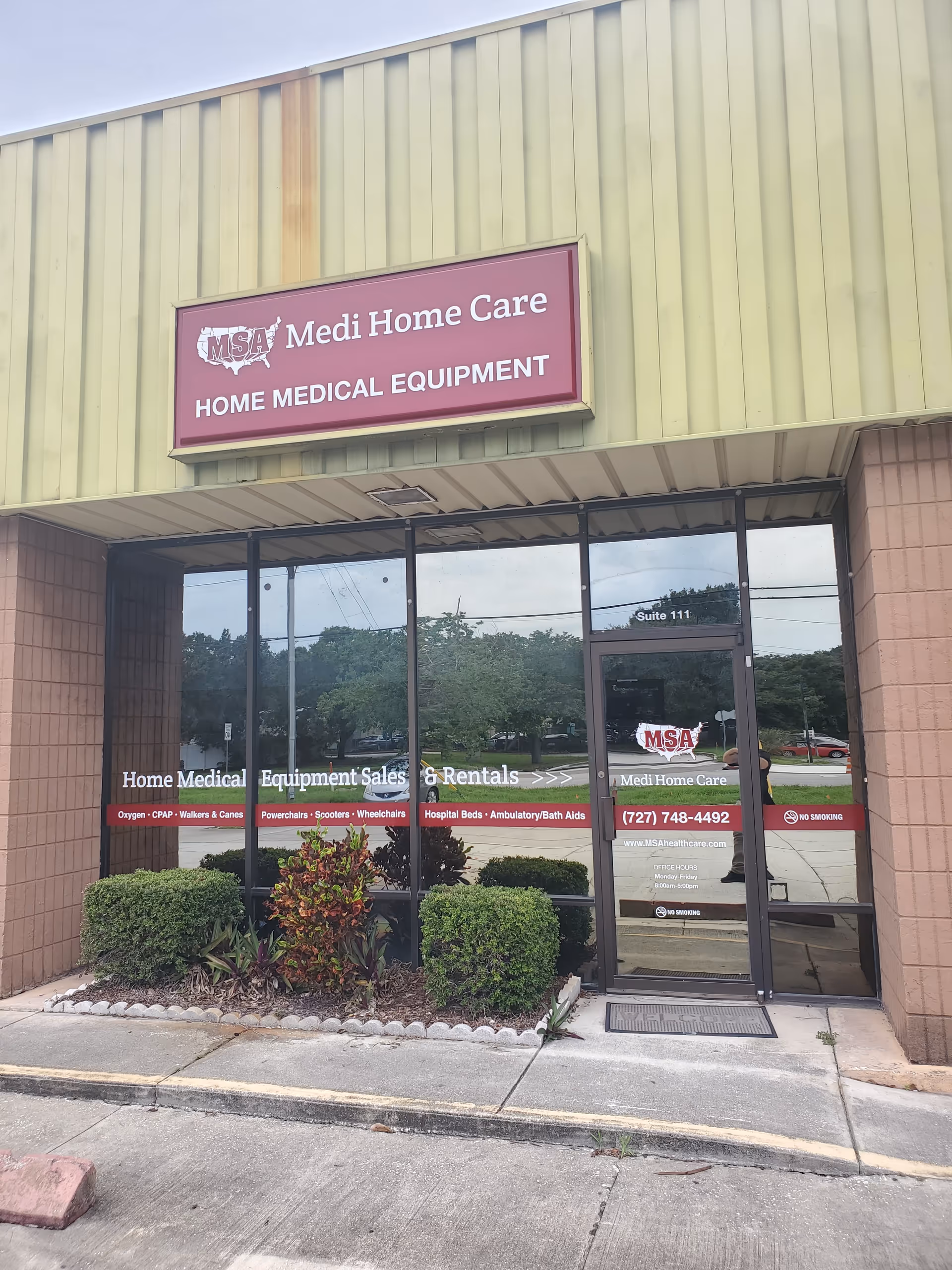 Exterior of Medi Home Care storefront with glass doors, sign, and landscaped entrance.