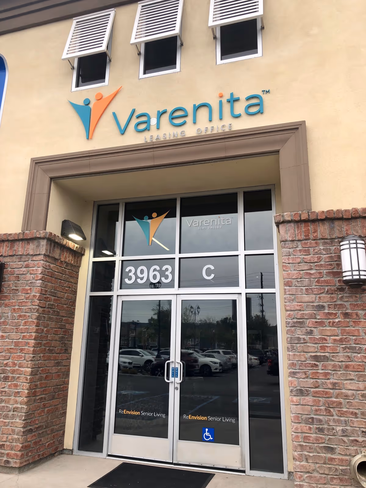 Facade of Varenita senior living entrance with logo and glass doors.