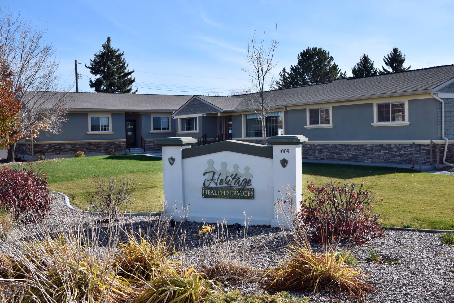 Front exterior of a single-story care facility with a sign and landscaped lawn.