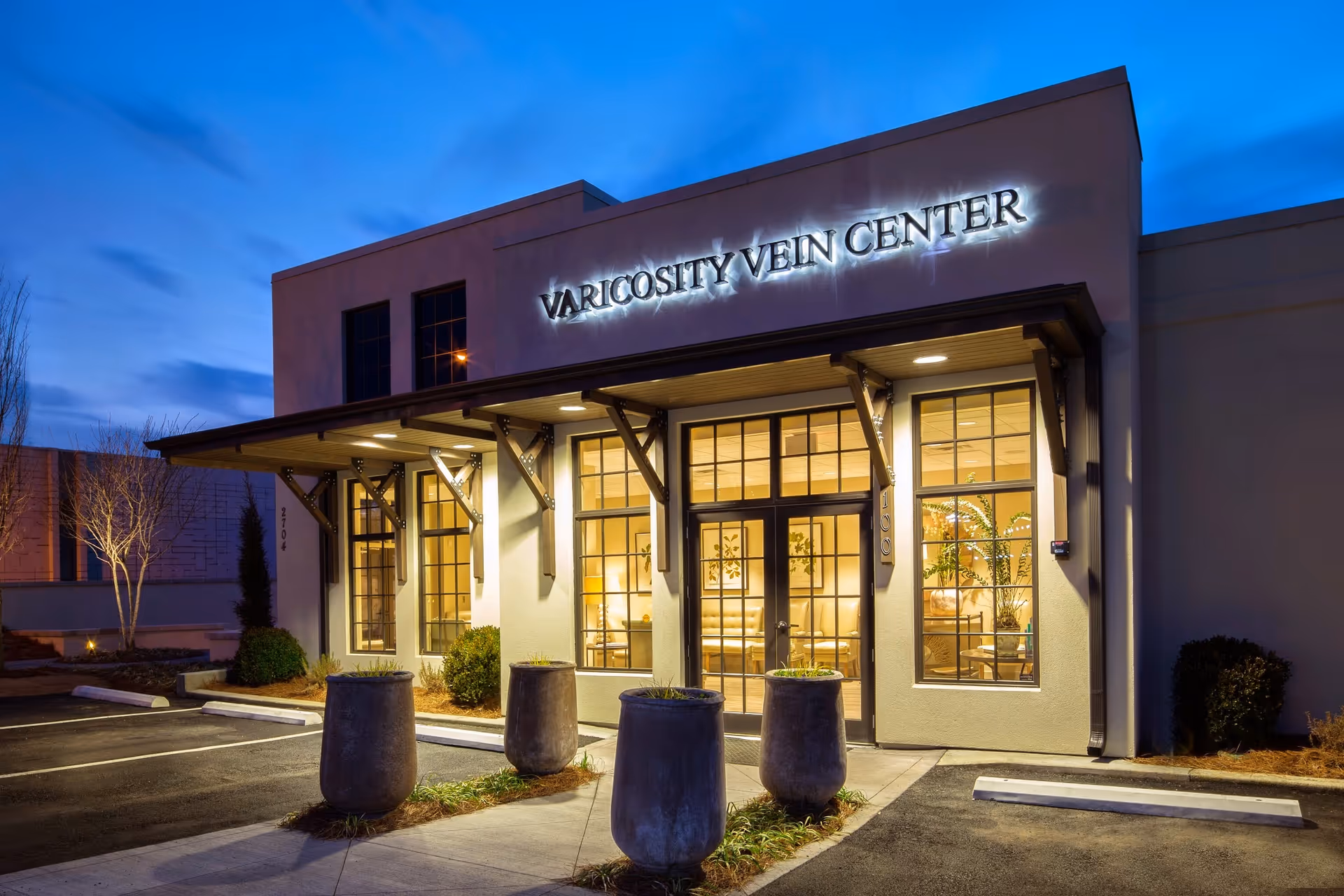 Exterior view of the Varicosity Vein Center storefront at dusk with illuminated sign