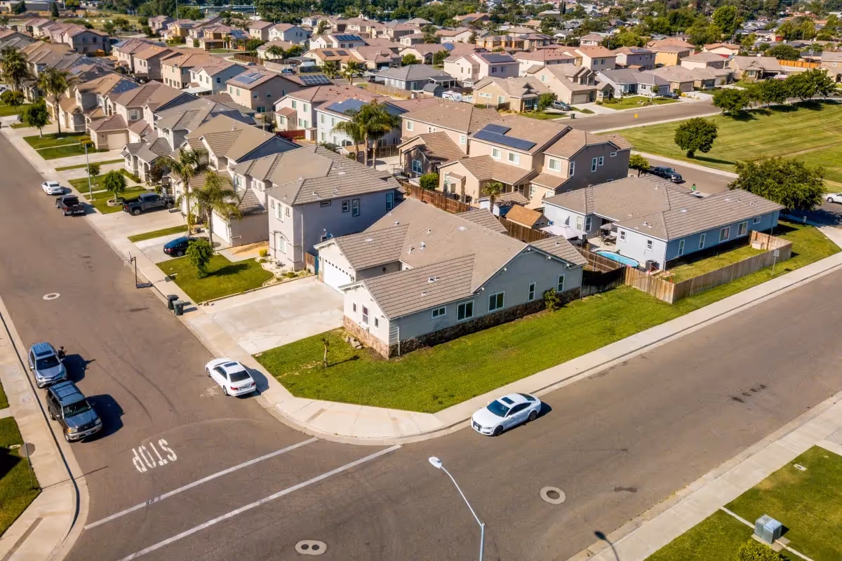 Aerial view of a suburban cul-de-sac with tan houses and green lawns.