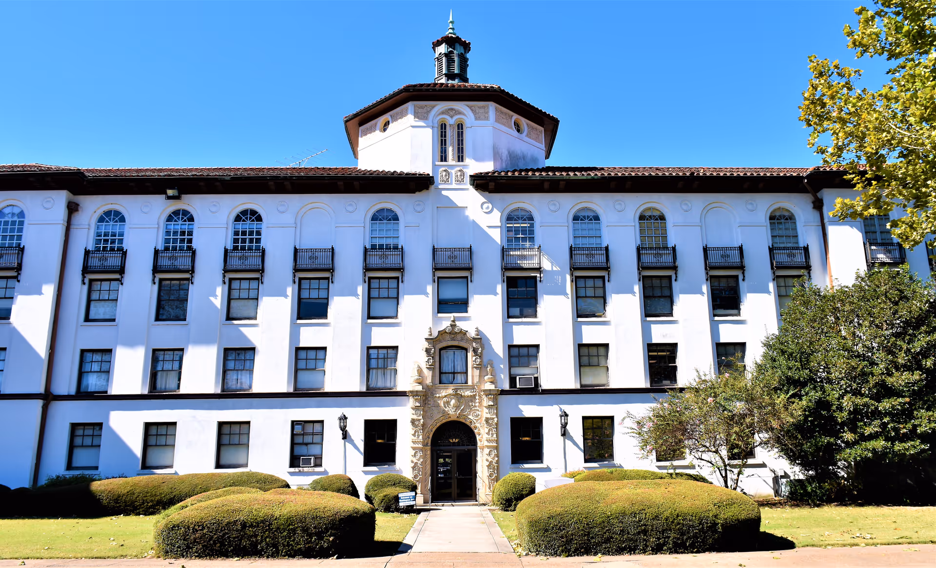 Front facade of Allegiance Specialty Hospital of Greenville, a white multi-story building with arched windows.