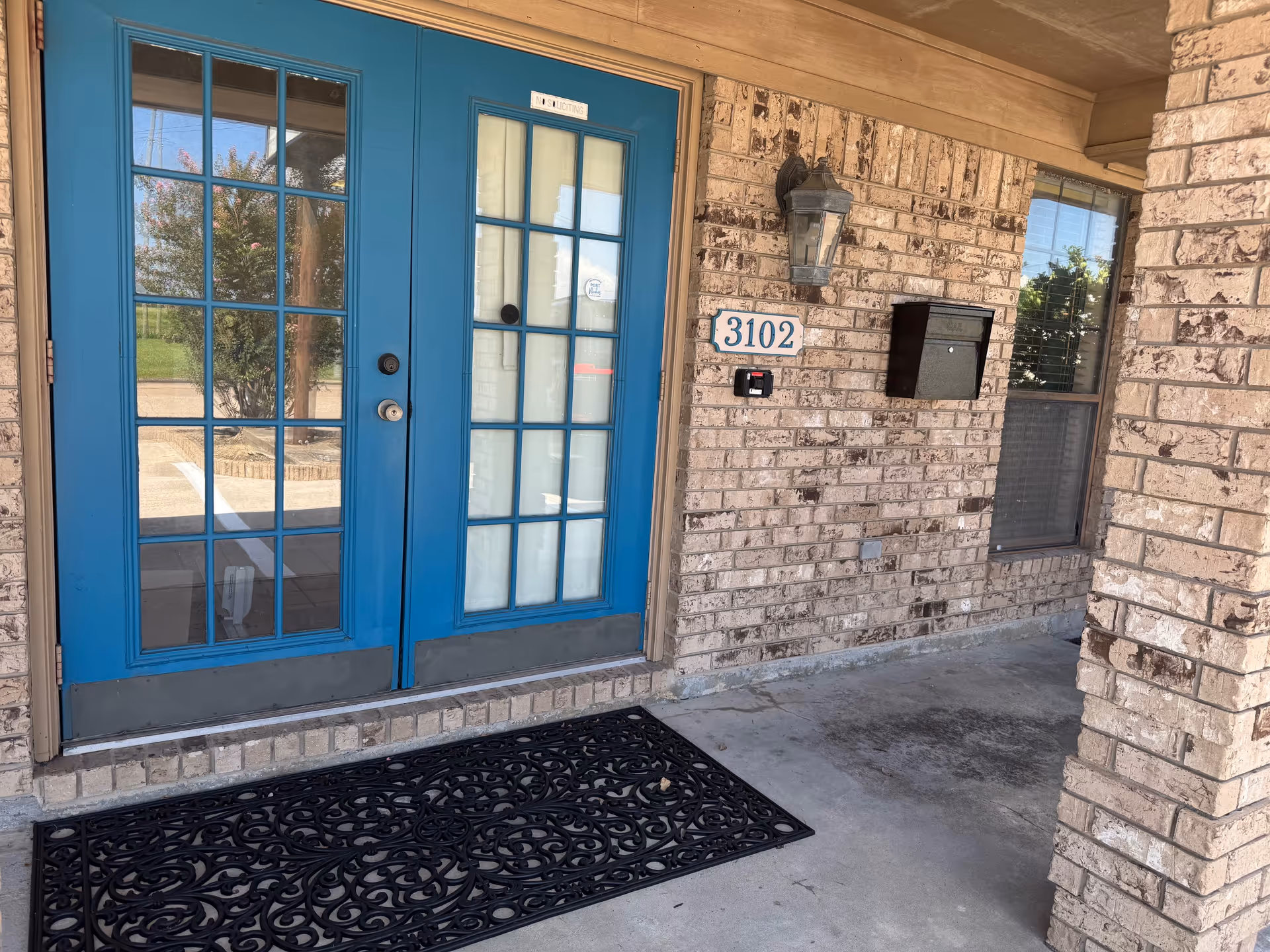 Blue French doors and brick exterior of a senior living facility entrance.
