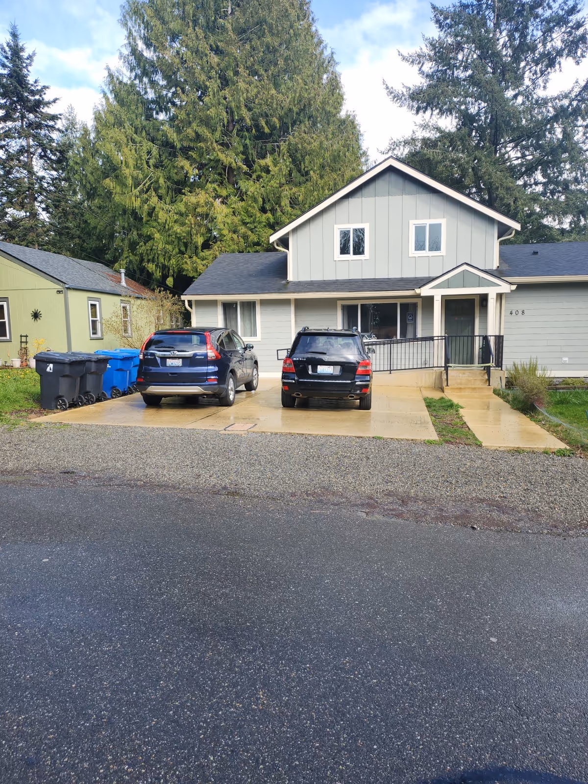 Front exterior of a gray two-story facility with cars parked in the driveway.