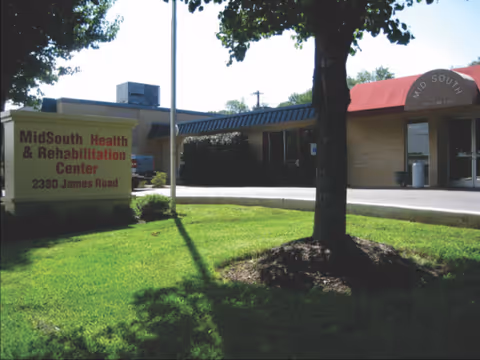 Exterior view of Midsouth Health & Rehabilitation Center with sign, entrance, and manicured lawn.