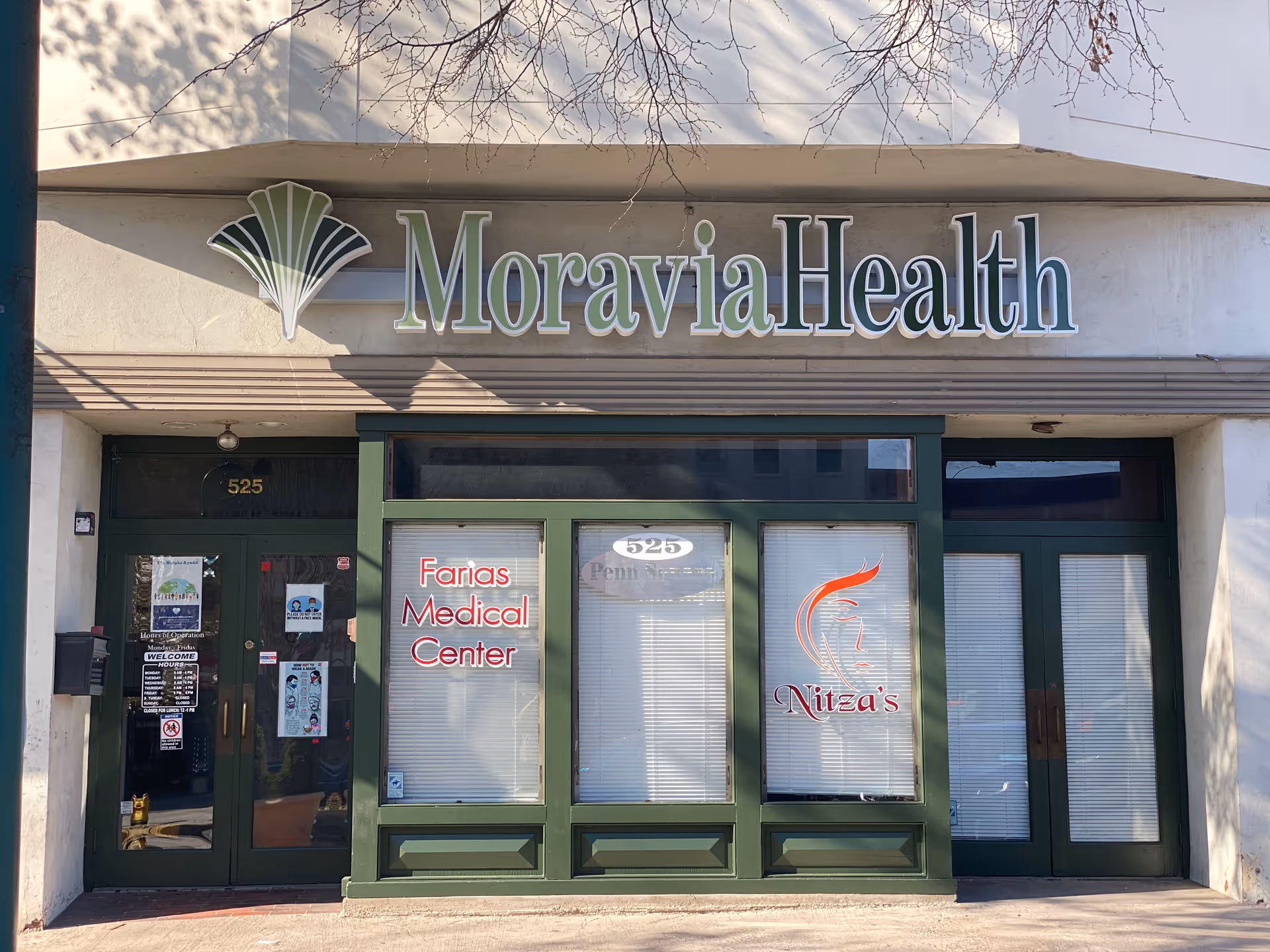 Facade of Moravia Health storefront with large sign and green-framed glass doors