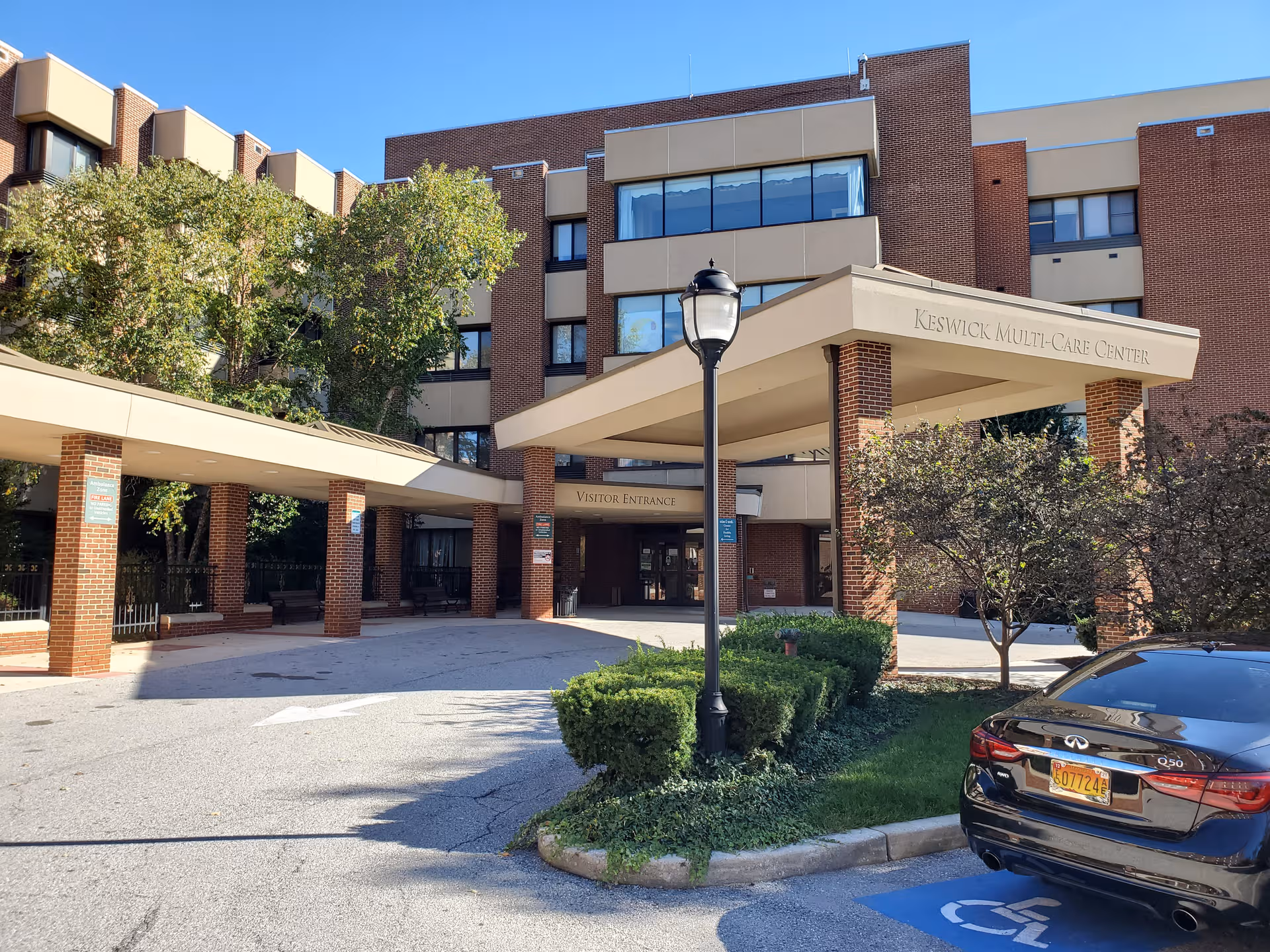 Keswick Multi-Care Center front entrance with a covered driveway, brick facade, and parked car.