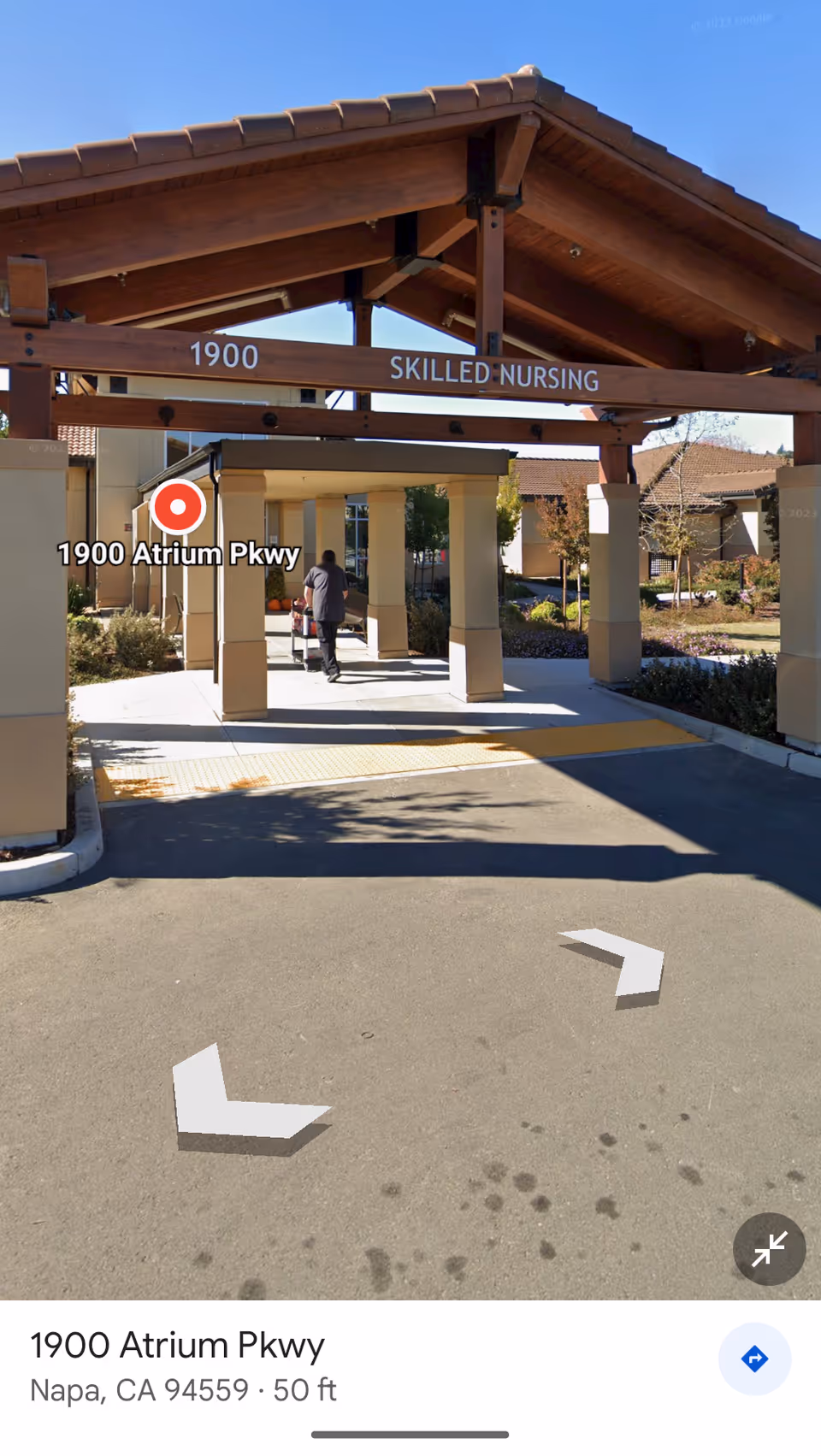Exterior entrance to Skilled Nursing facility with wooden porte-cochere and people nearby.