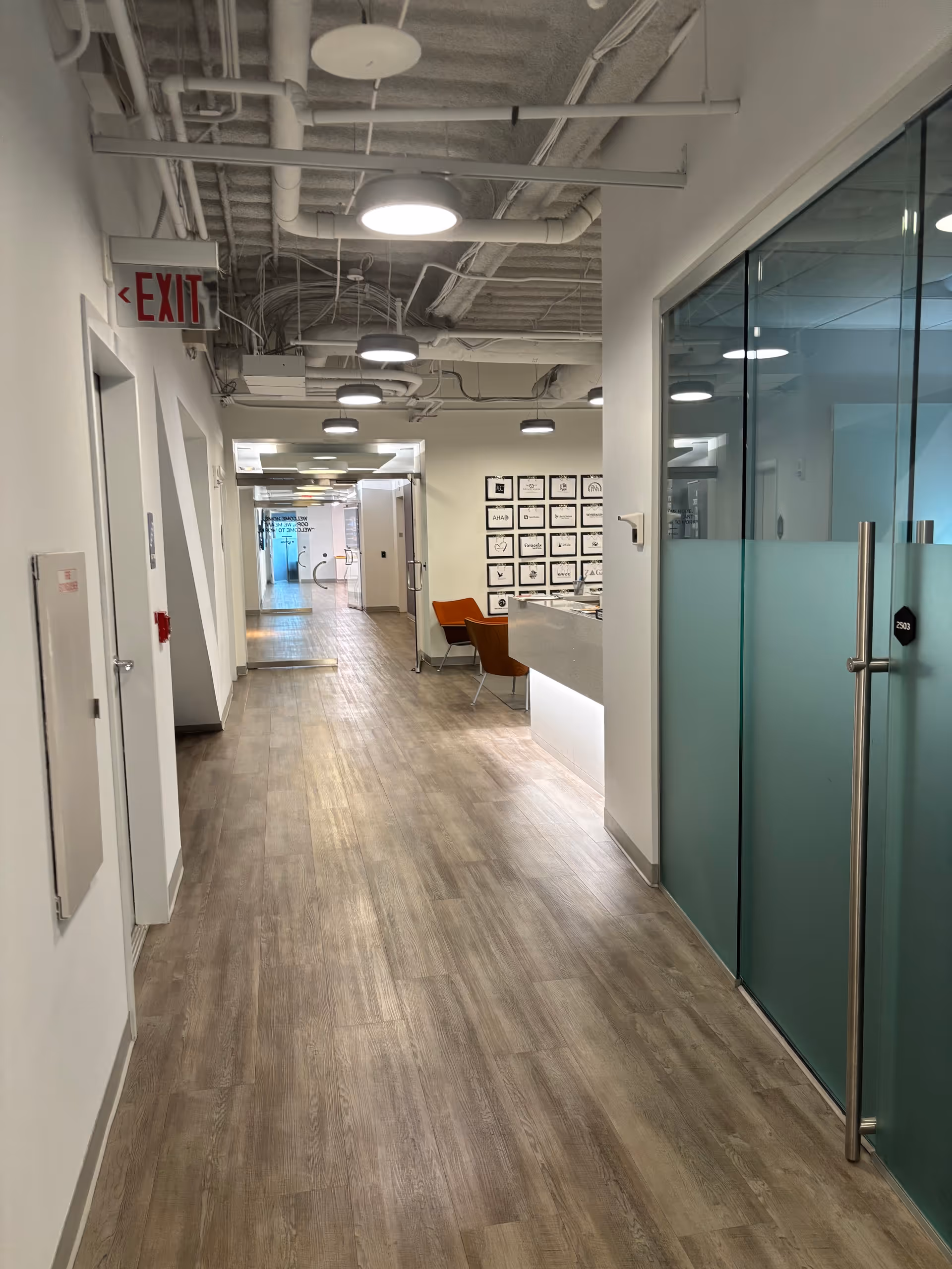 Long hallway in a senior living facility with a reception desk and orange chairs.