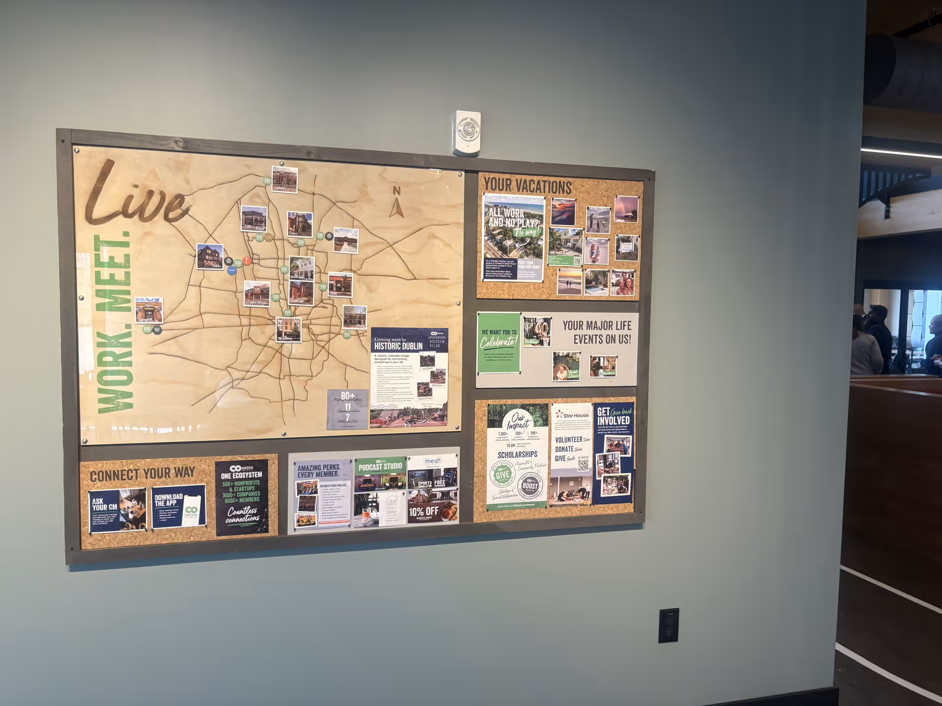 Indoor hallway with a large cork bulletin board displaying maps and notices.