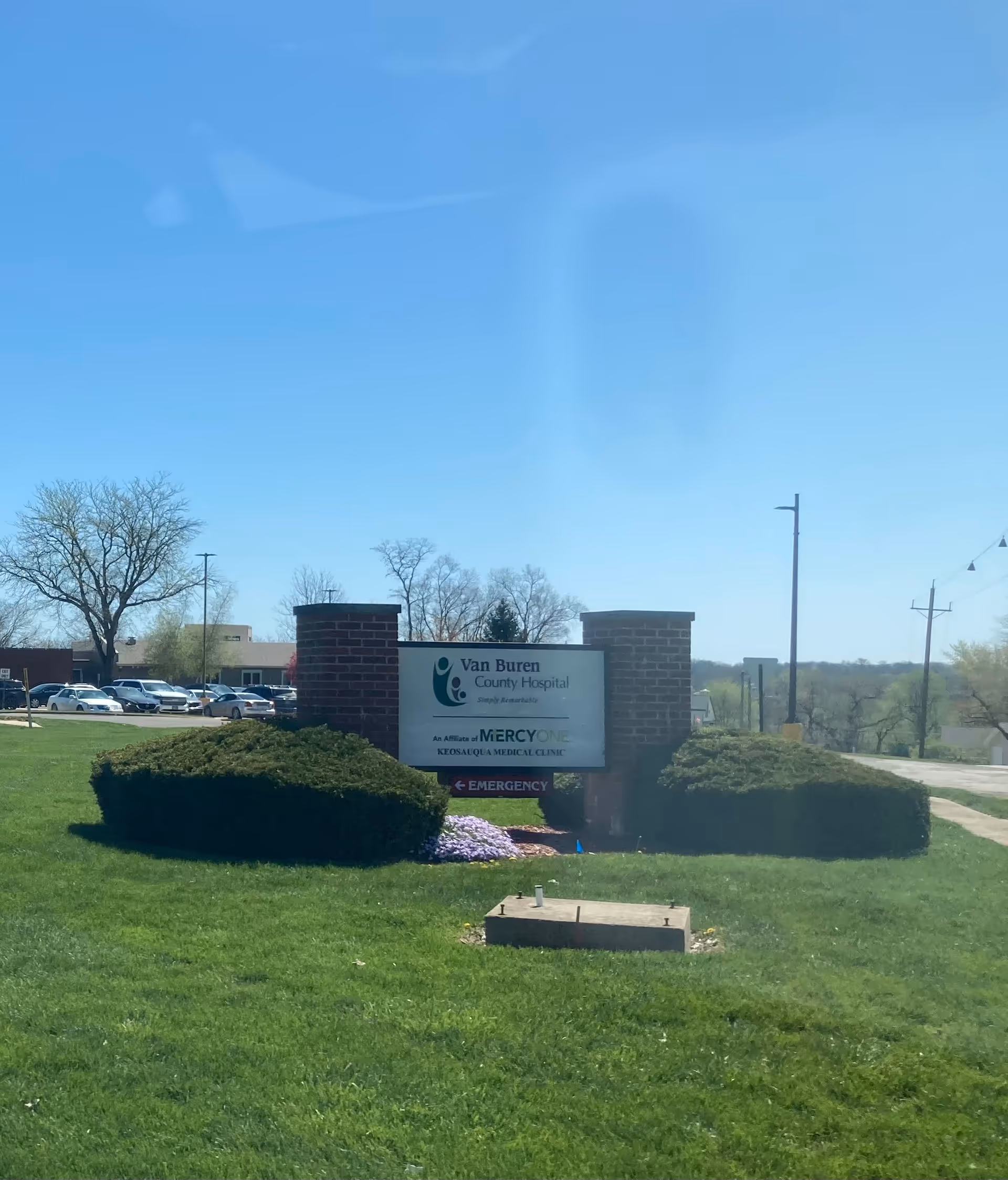 Front view of Van Buren County Hospital entrance with sign, shrubs, and a parking lot.