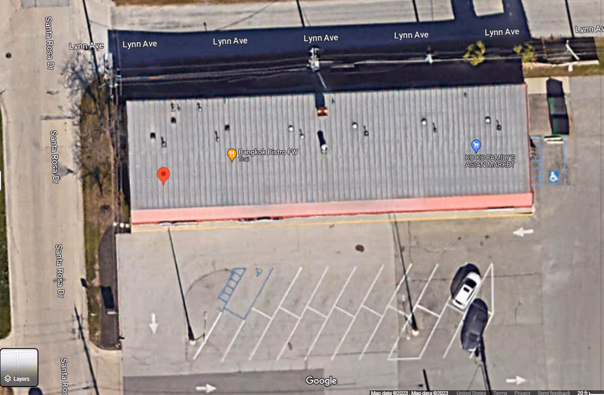 A satellite view of a gray-roofed building with a large parking lot.