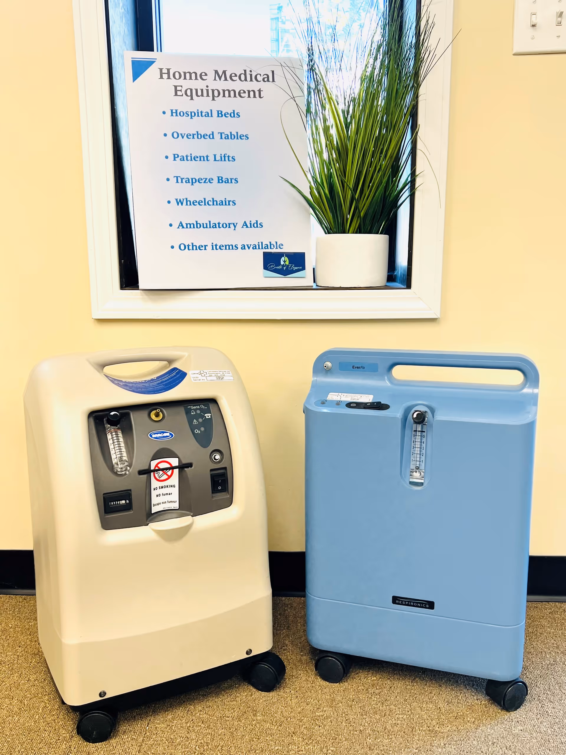 Two portable medical devices sit on the floor beside a sign in a yellow hallway.