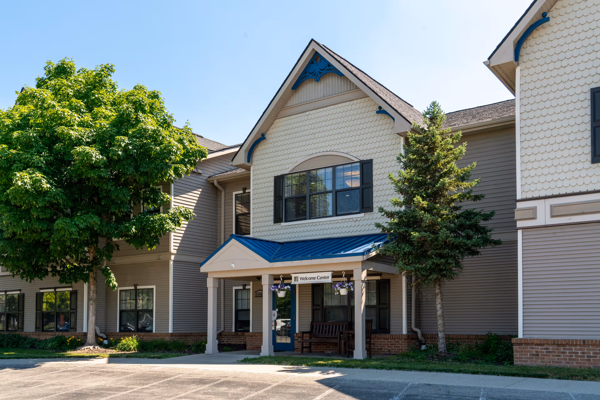 Exterior view of Commonwealth Senior Living at New Baltimore with entrance, trees, and a blue awning.