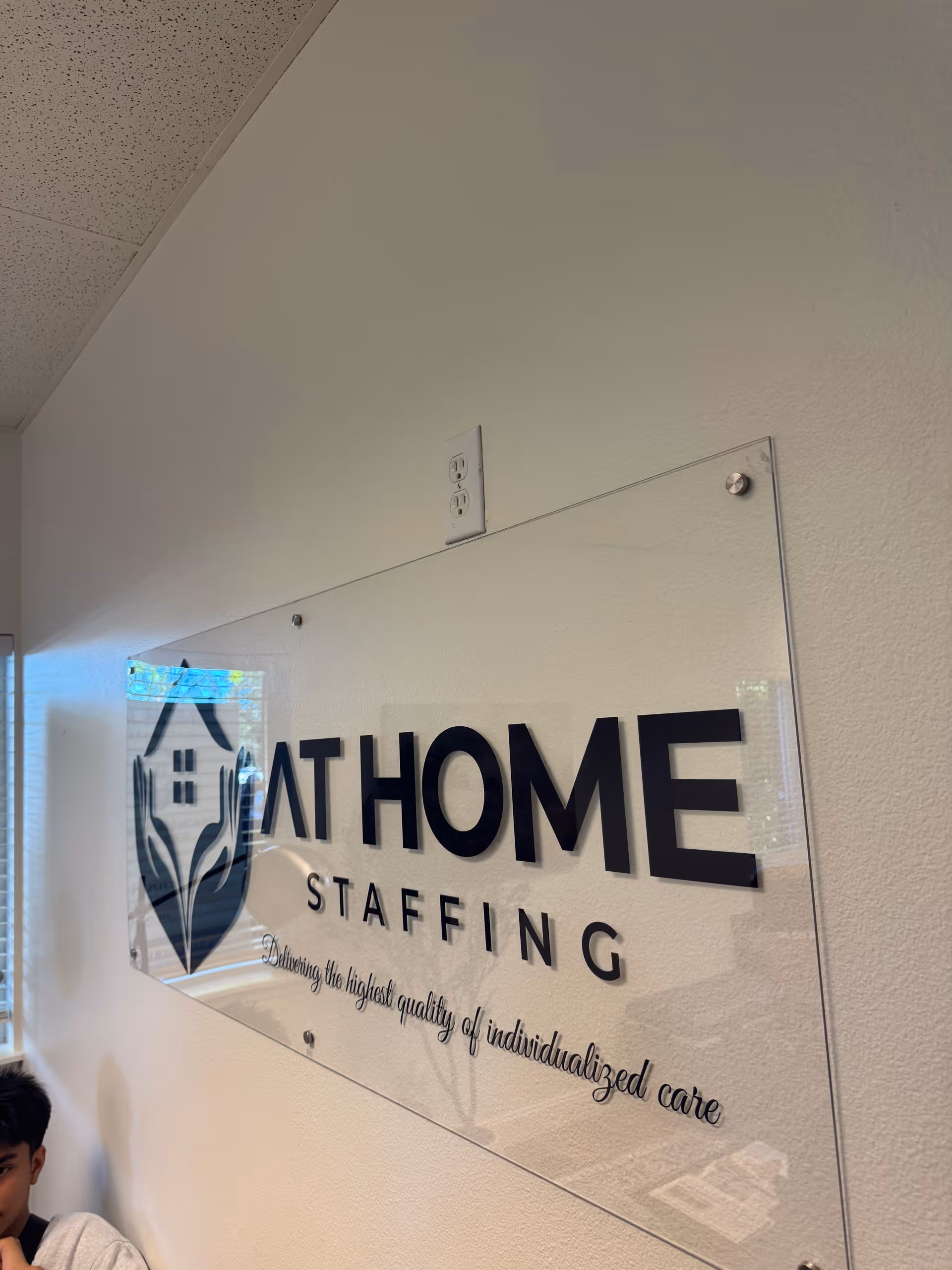Interior hallway with a large acrylic sign displaying AT HOME STAFFING.