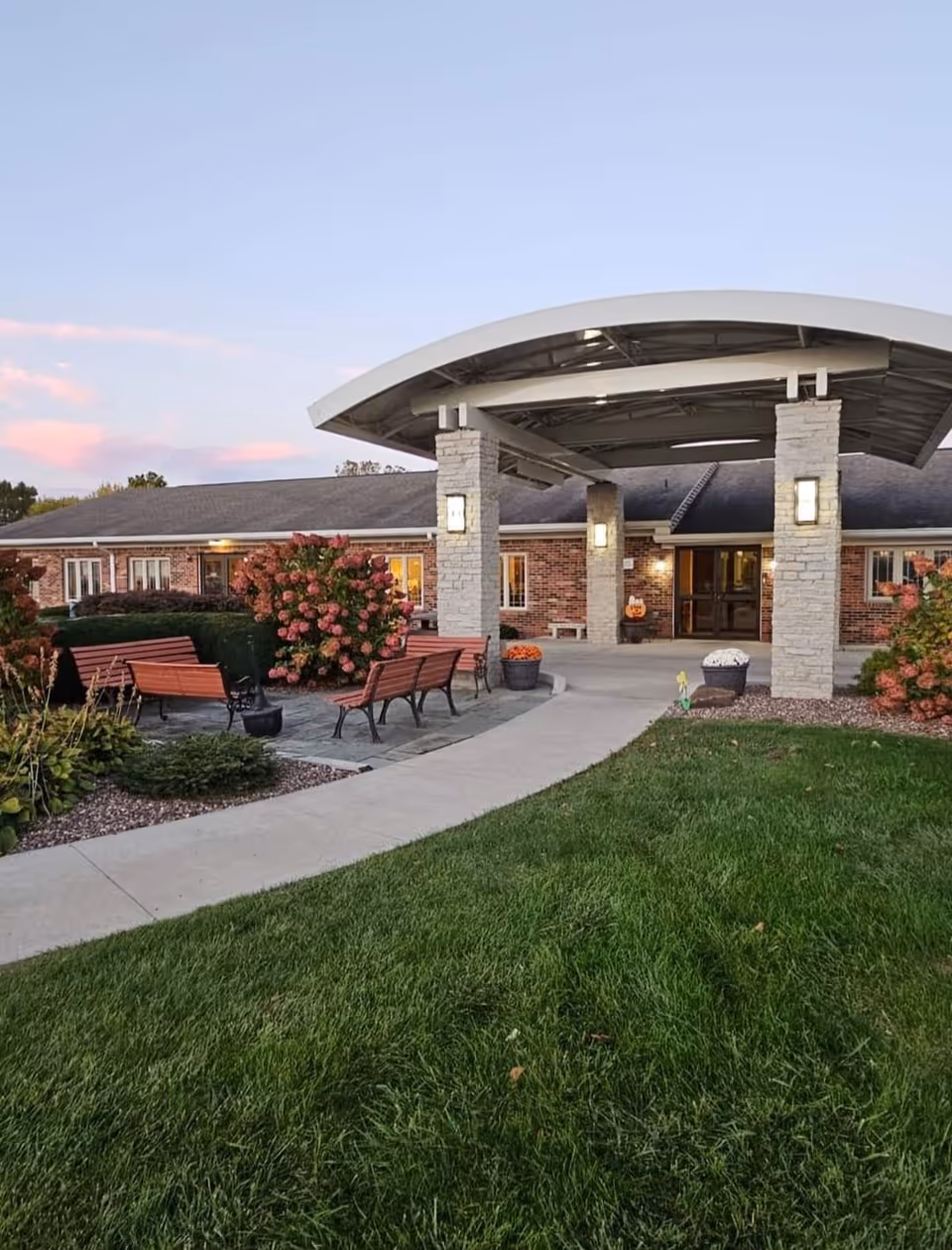 Exterior view of Willows of Greensburg entrance with benches and landscaped walkway