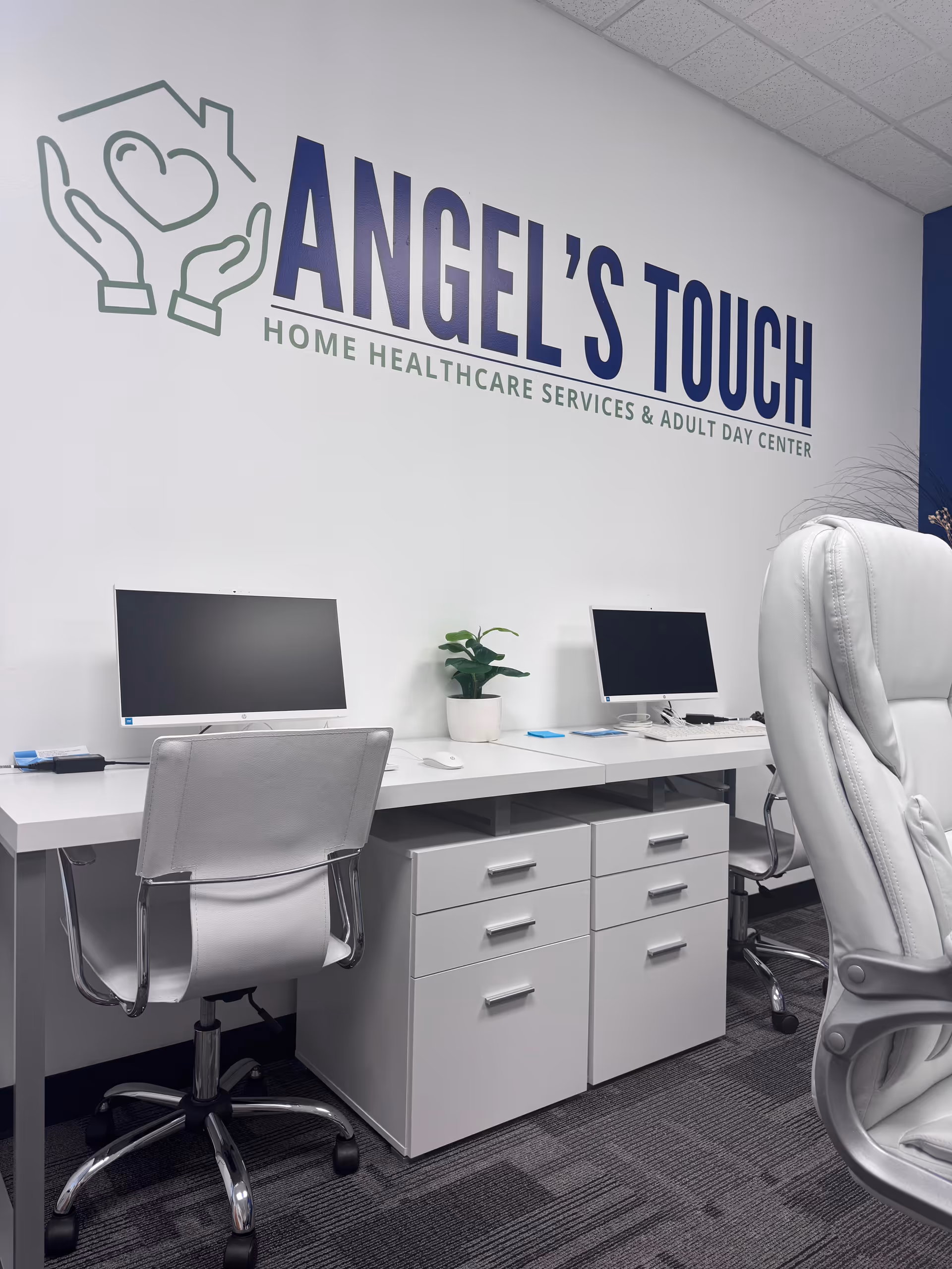 Front desk area with two computers and the Angel's Touch logo on wall.