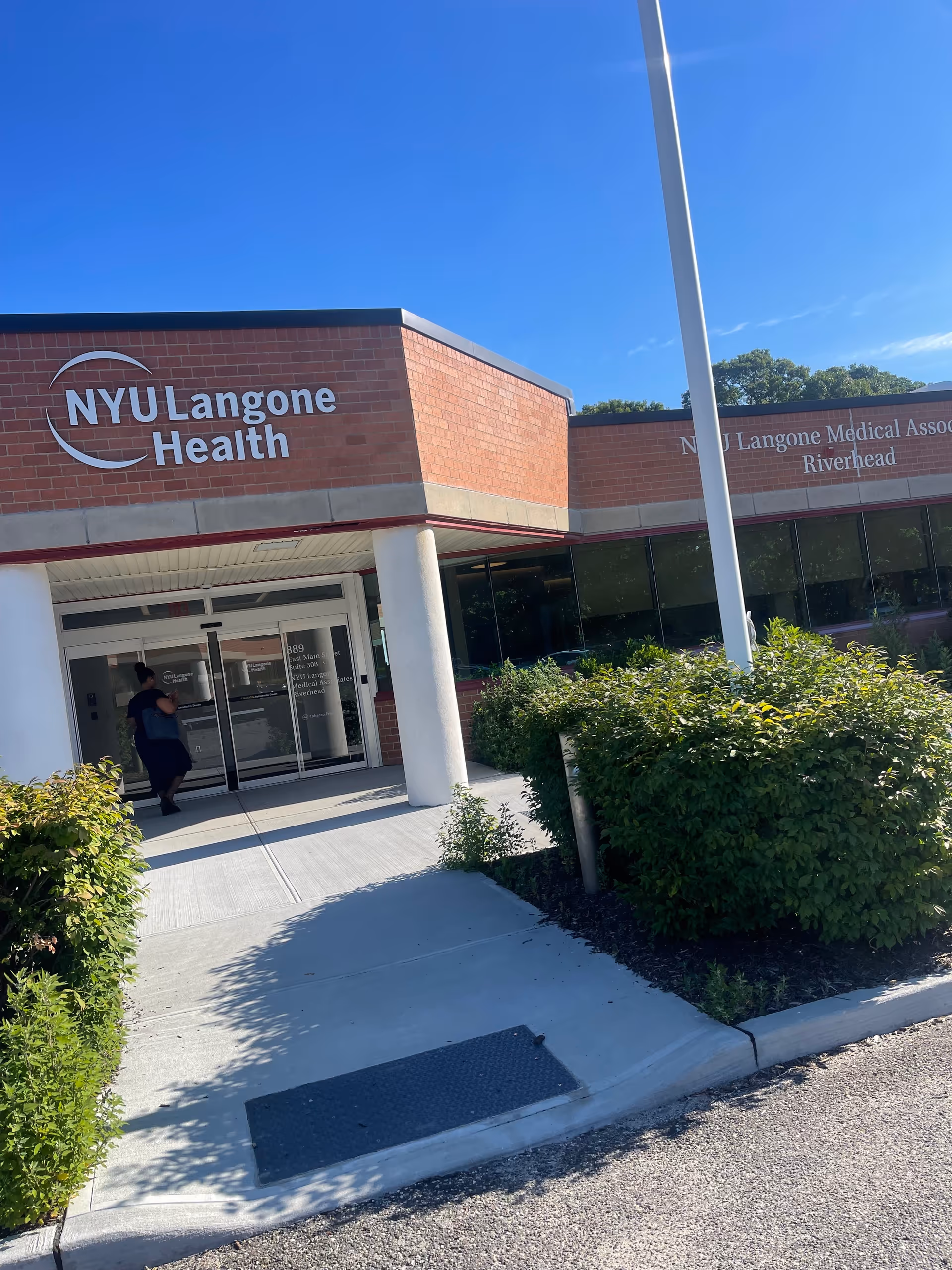 Exterior view of NYU Langone Health Riverhead entrance with glass doors and brick facade.