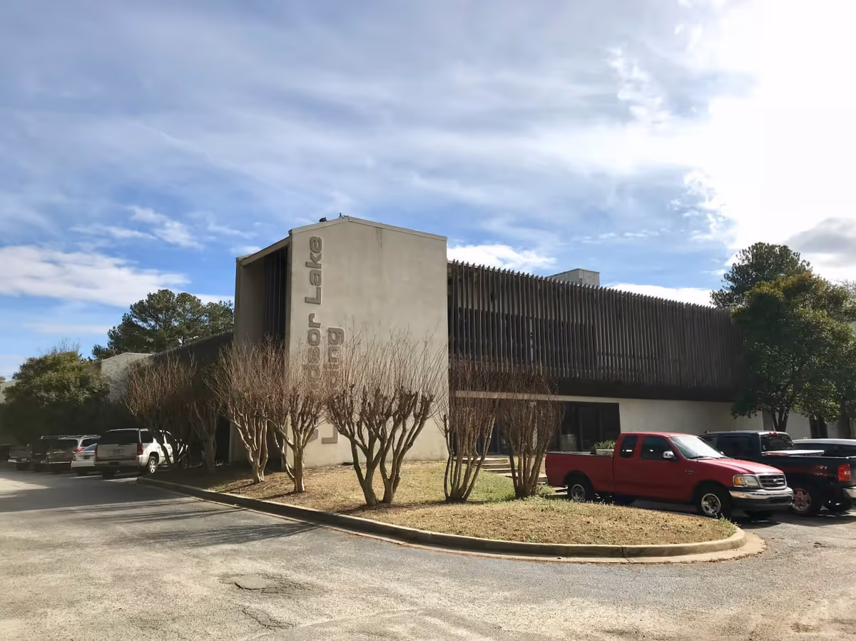 Exterior view of a modern senior living facility with parked cars and landscaping.
