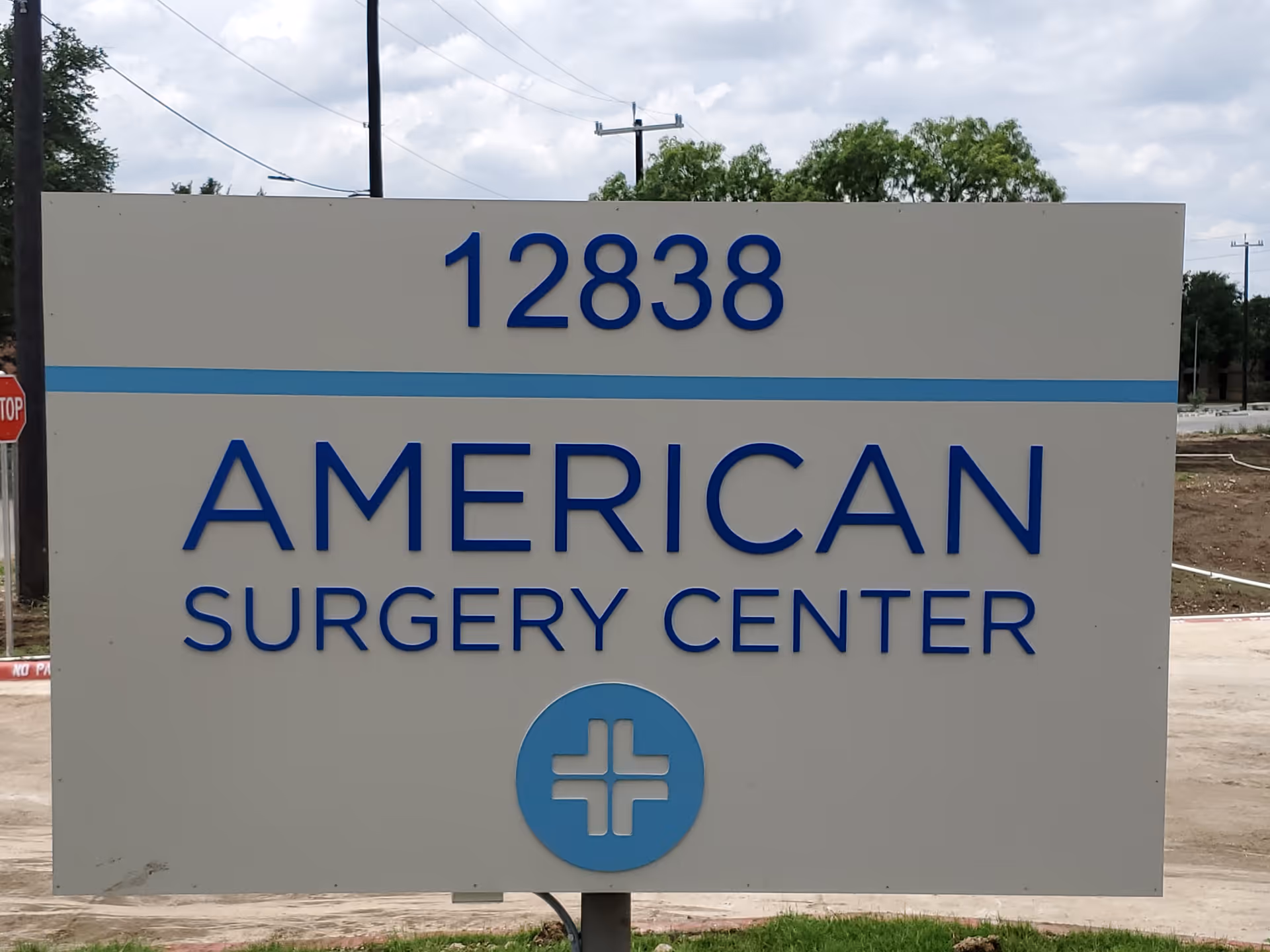 Large outdoor sign with blue lettering reading AMERICAN SURGERY CENTER and a circular logo