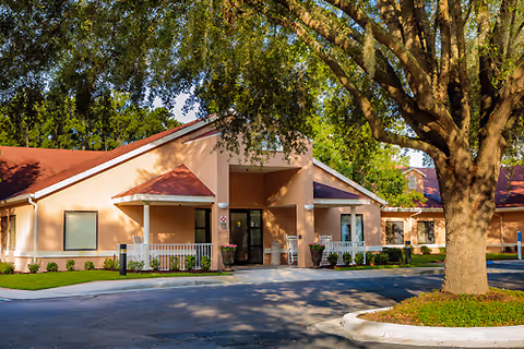 Sunlit exterior view of Solaris Healthcare Lake City entrance with trees and landscaping.