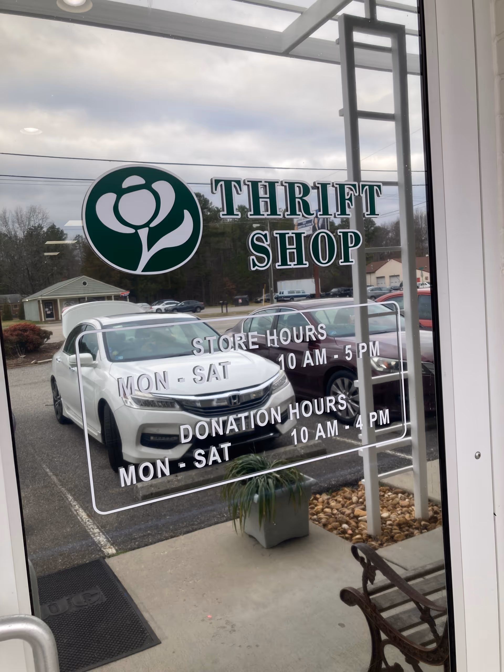 Front window of a thrift shop displaying THRIFT SHOP sign and store hours
