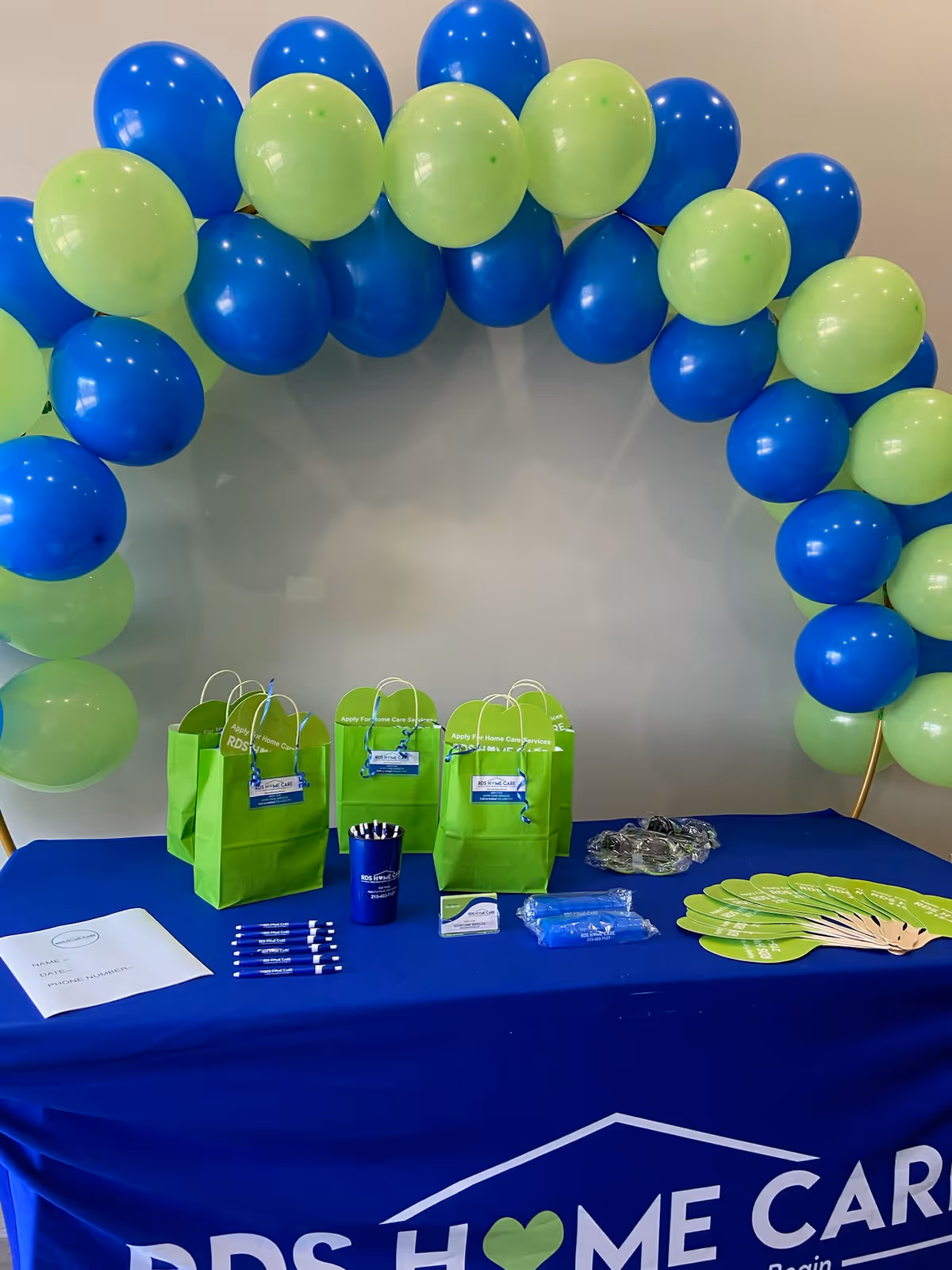 Indoor promotional display with a blue table, balloon arch, and RDS Home Care materials.