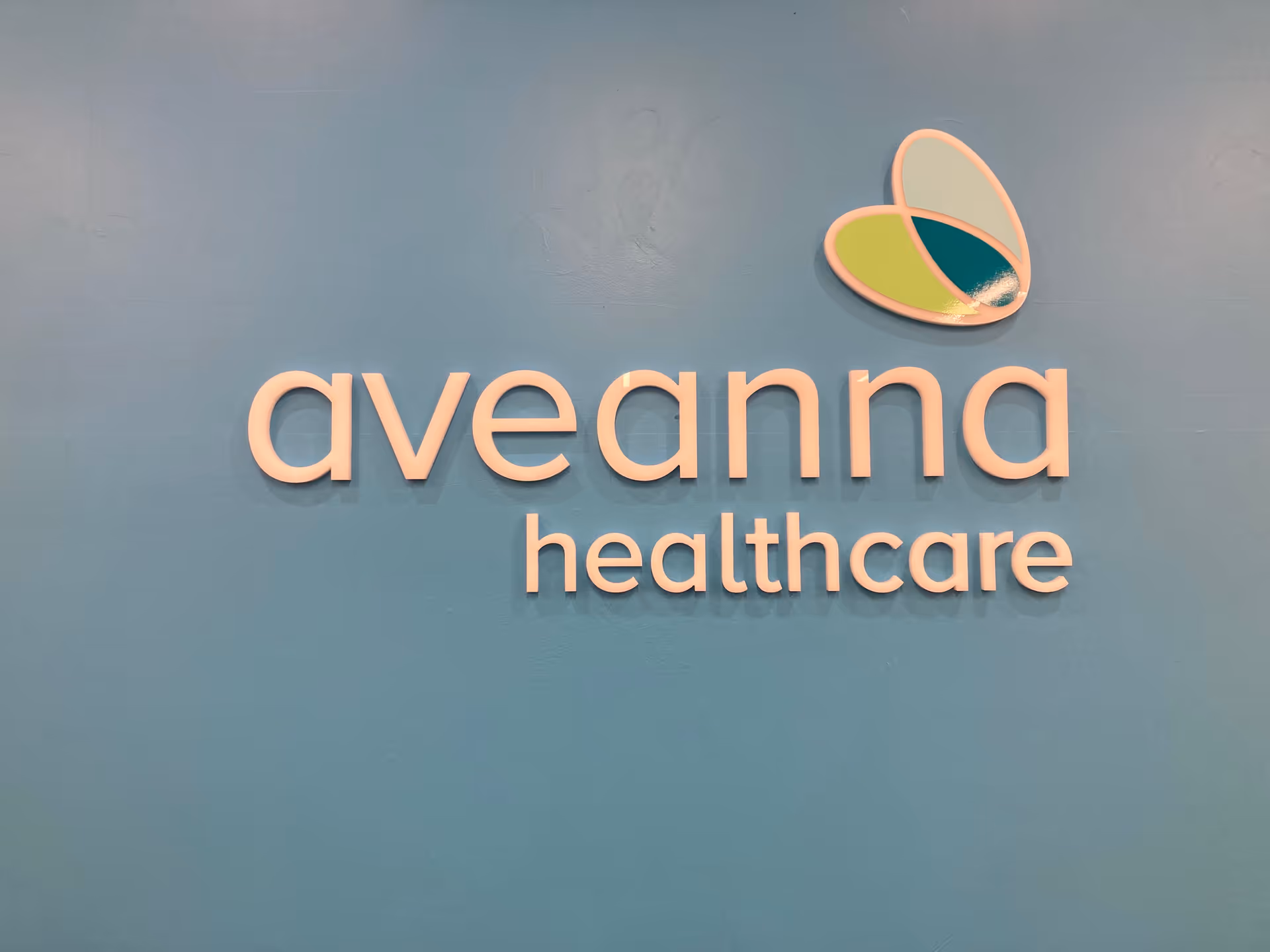 Blue interior wall with Aveanna Healthcare sign and butterfly logo.