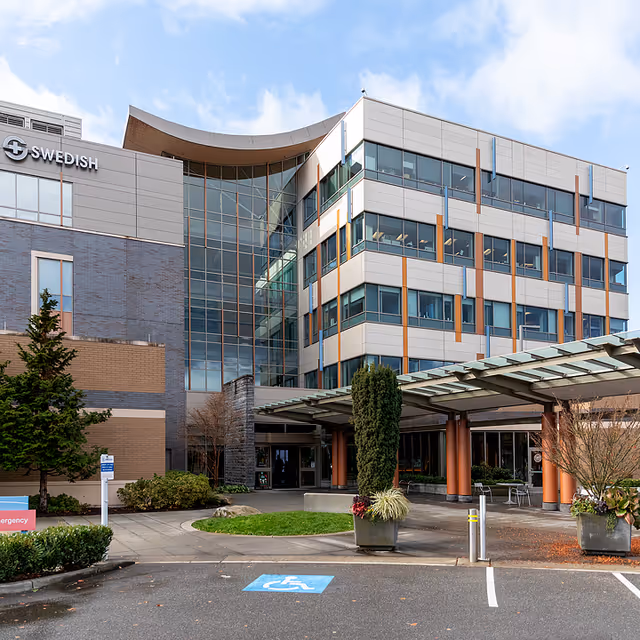 Modern multi-story medical building exterior with glass entrance and landscaped entryway.