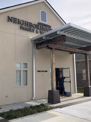 Exterior view of Neighborhood Health building entrance with a staff member at the door.