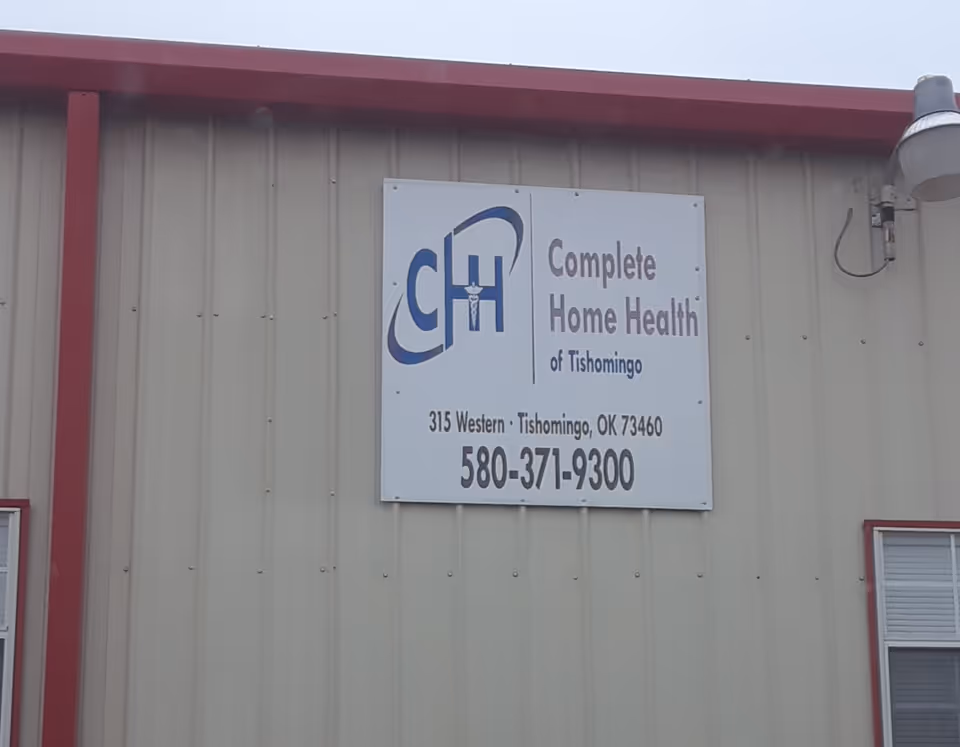 Exterior view of a beige building with a large sign reading Complete Home Health of Tishomingo.