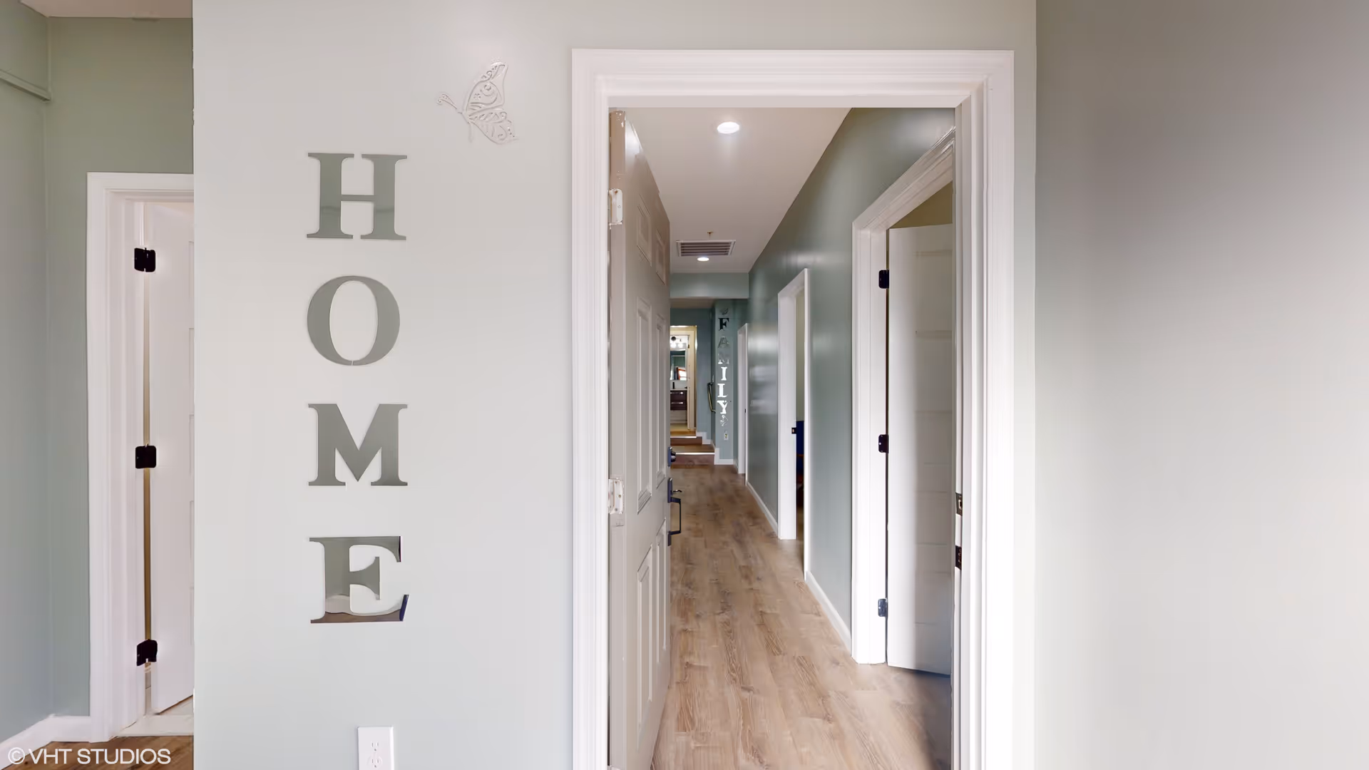 Light green hallway with multiple doors and large HOME letters along the left wall.