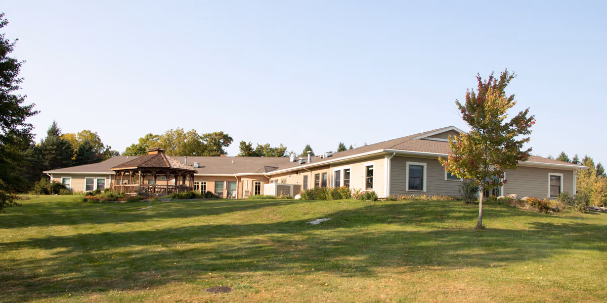 Exterior view of a single-story senior living facility with a gazebo and lawn.