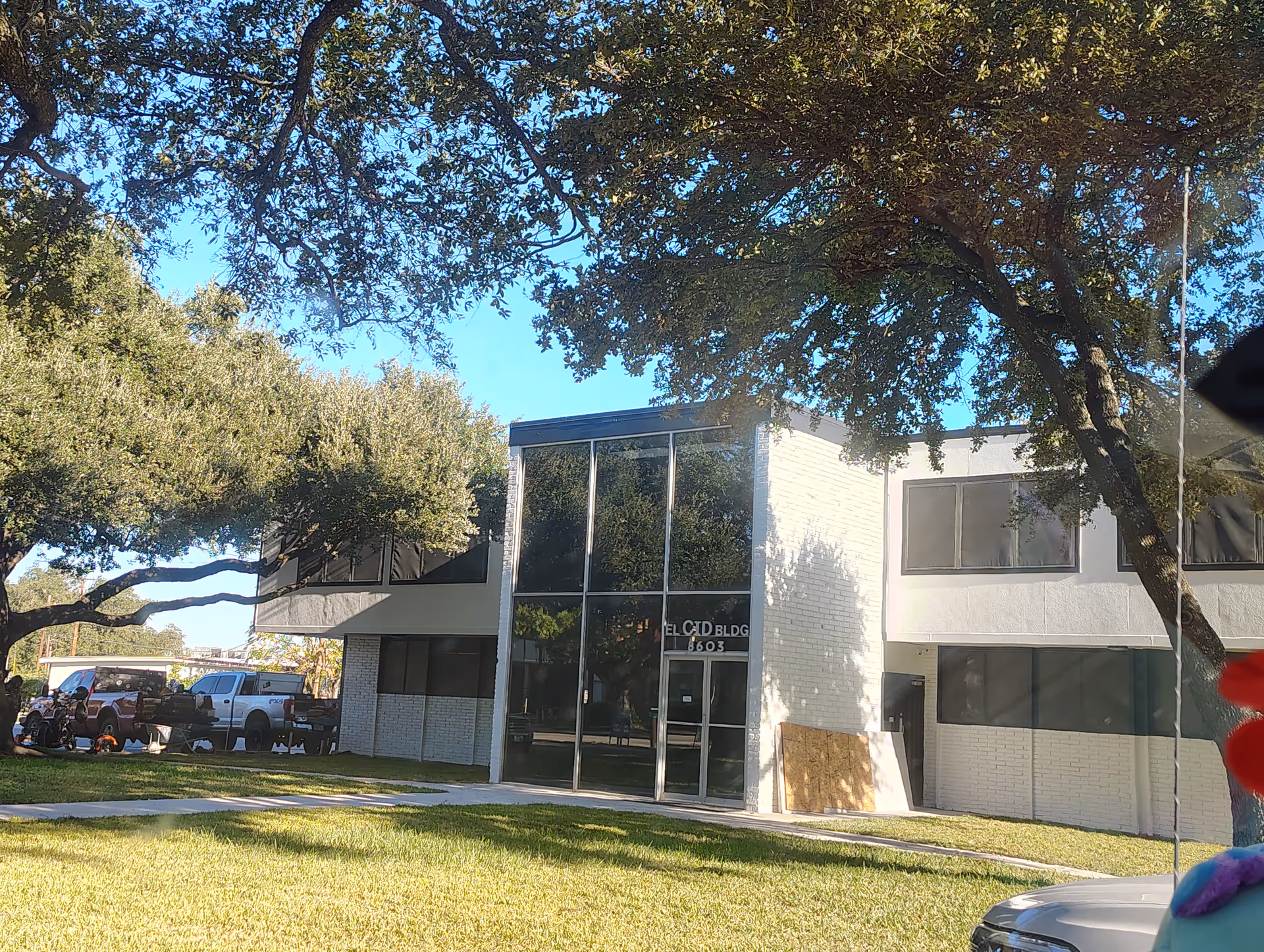 Modern two-story senior living building with glass entrance, trees, and a parking area